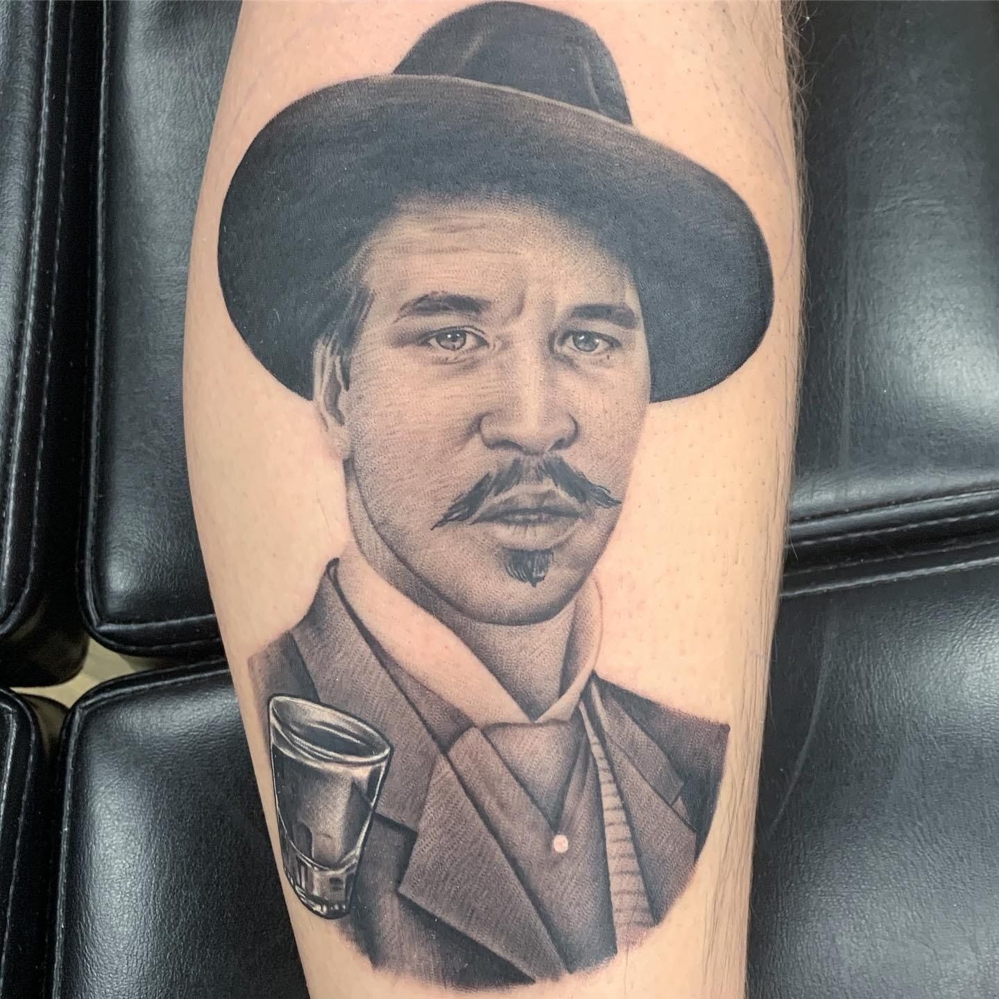 A tattoo of a man wearing a hat and holding a cup