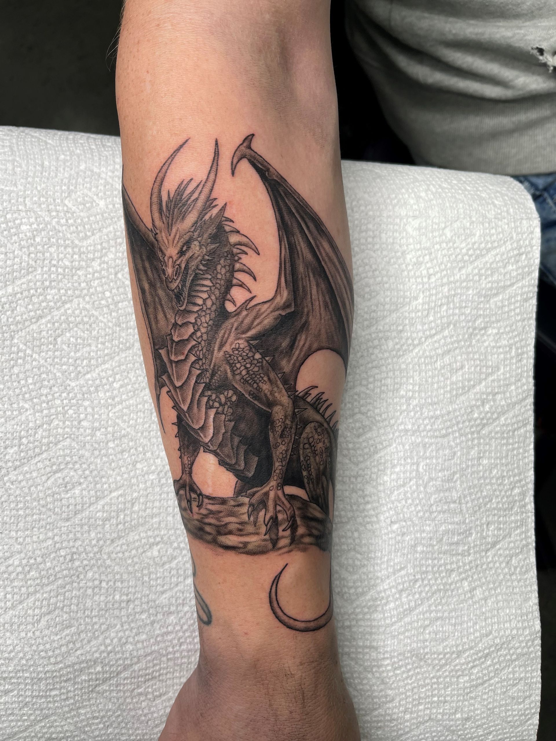 A man has a tattoo of a dragon on his forearm.