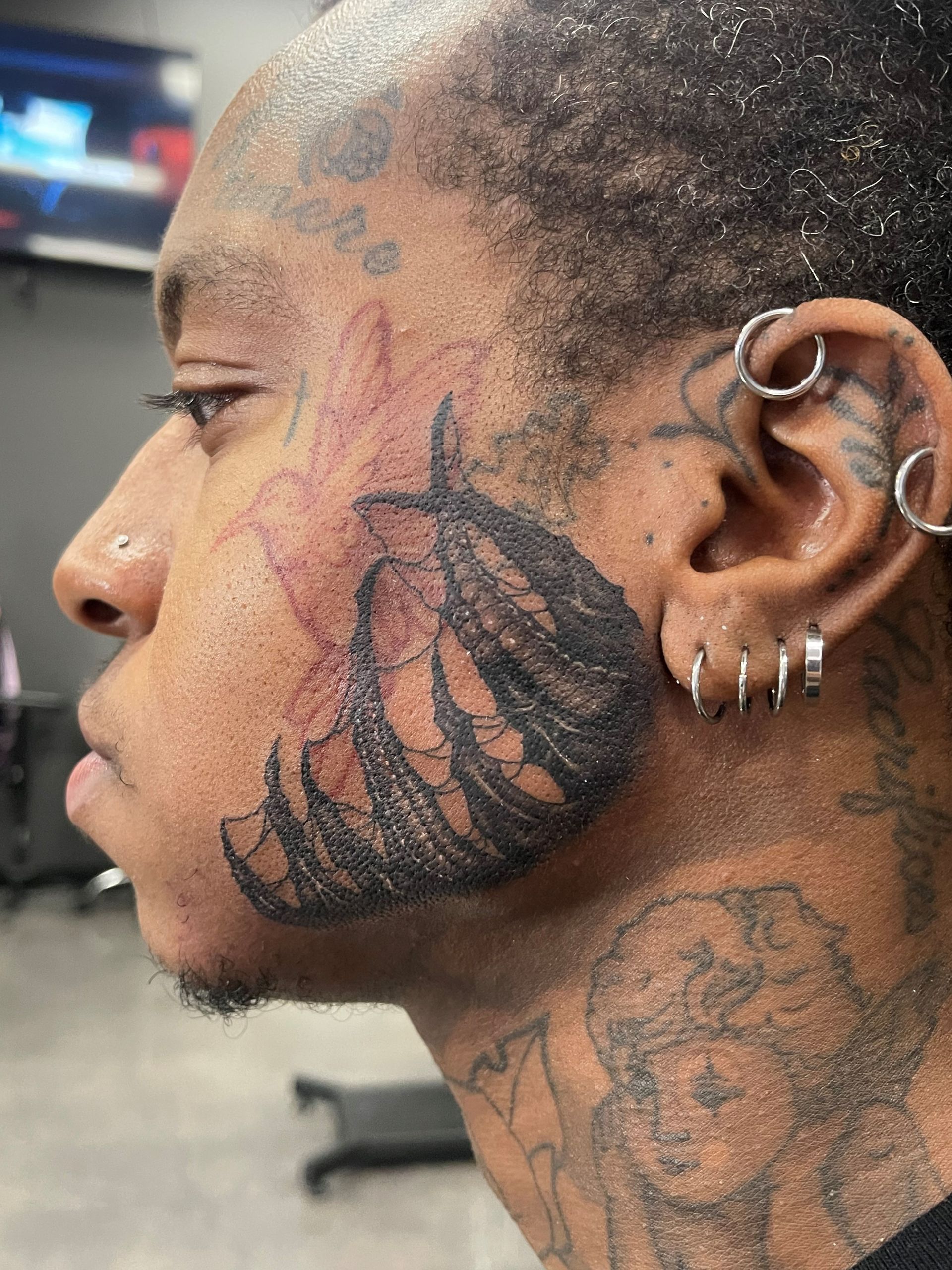 A man has a tattoo on his face and neck.