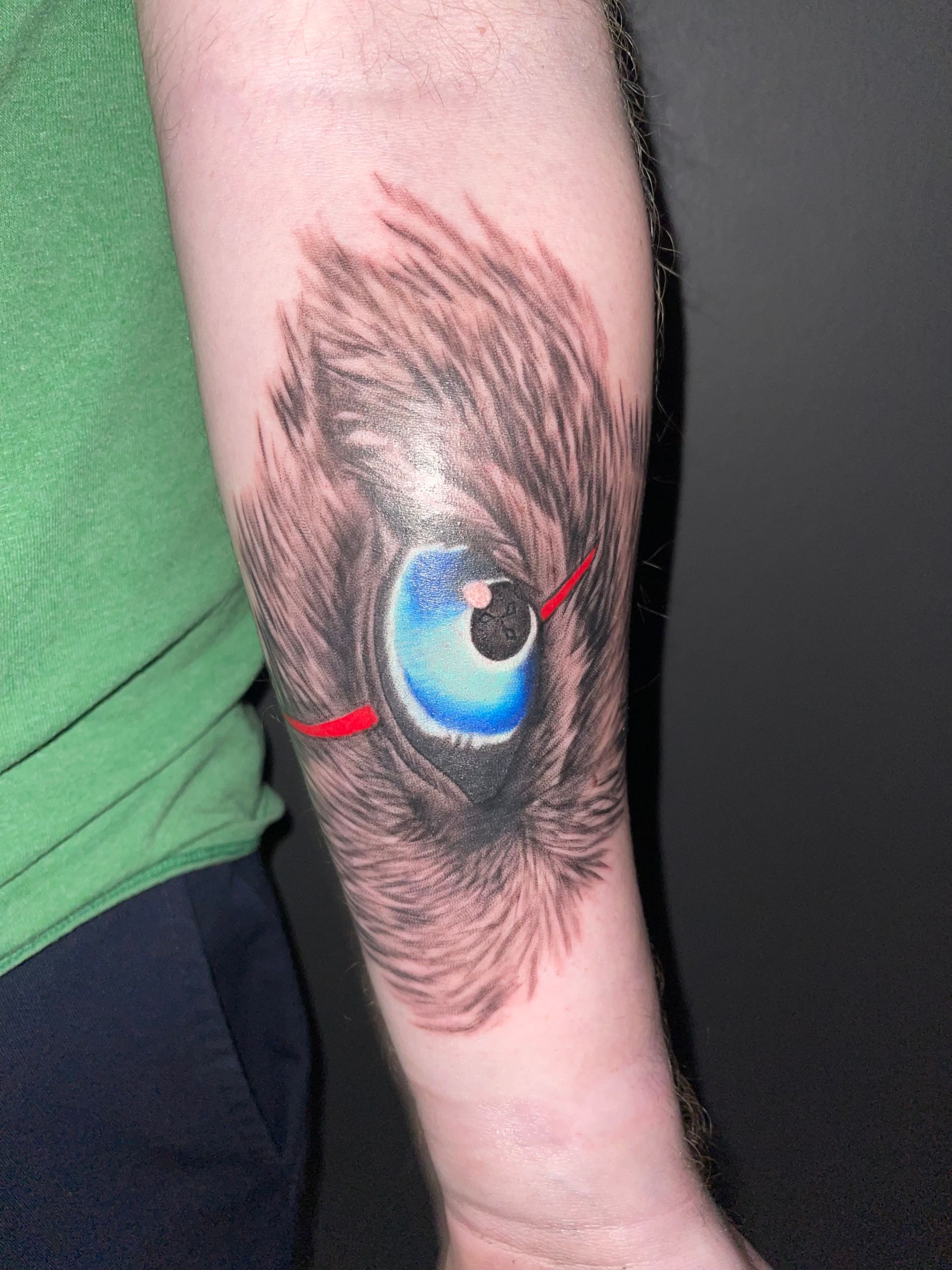 A person has a tattoo of a cat 's eye on their forearm.