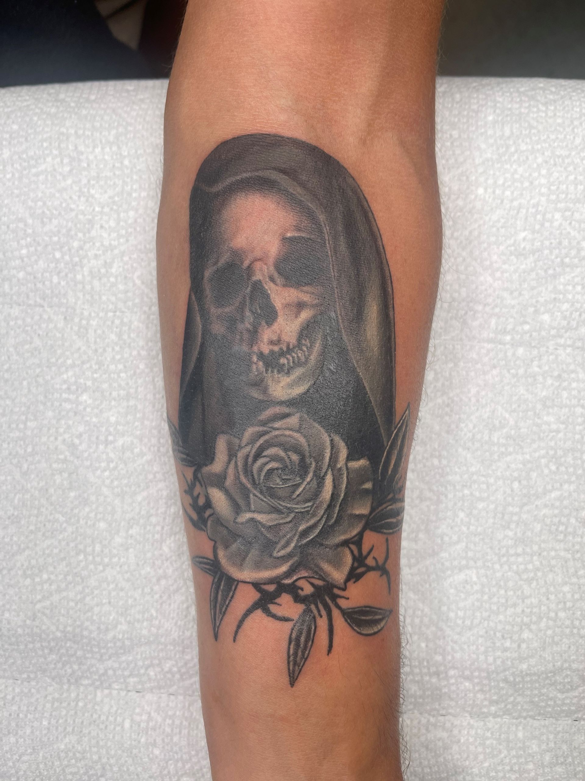 A person has a tattoo of a skull and a rose on their arm.