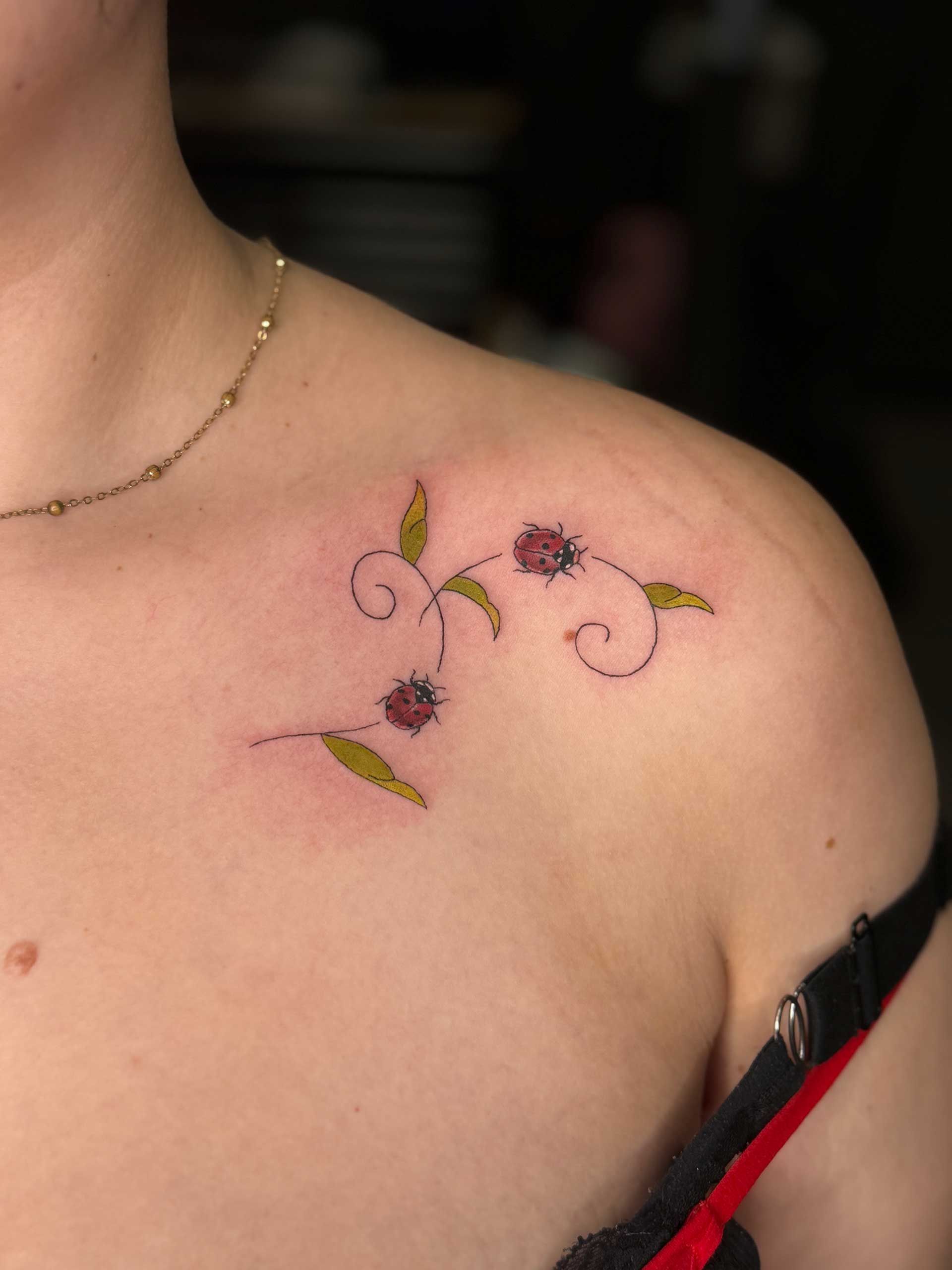 Shoulder with a tattoo of ladybugs near the collarbone