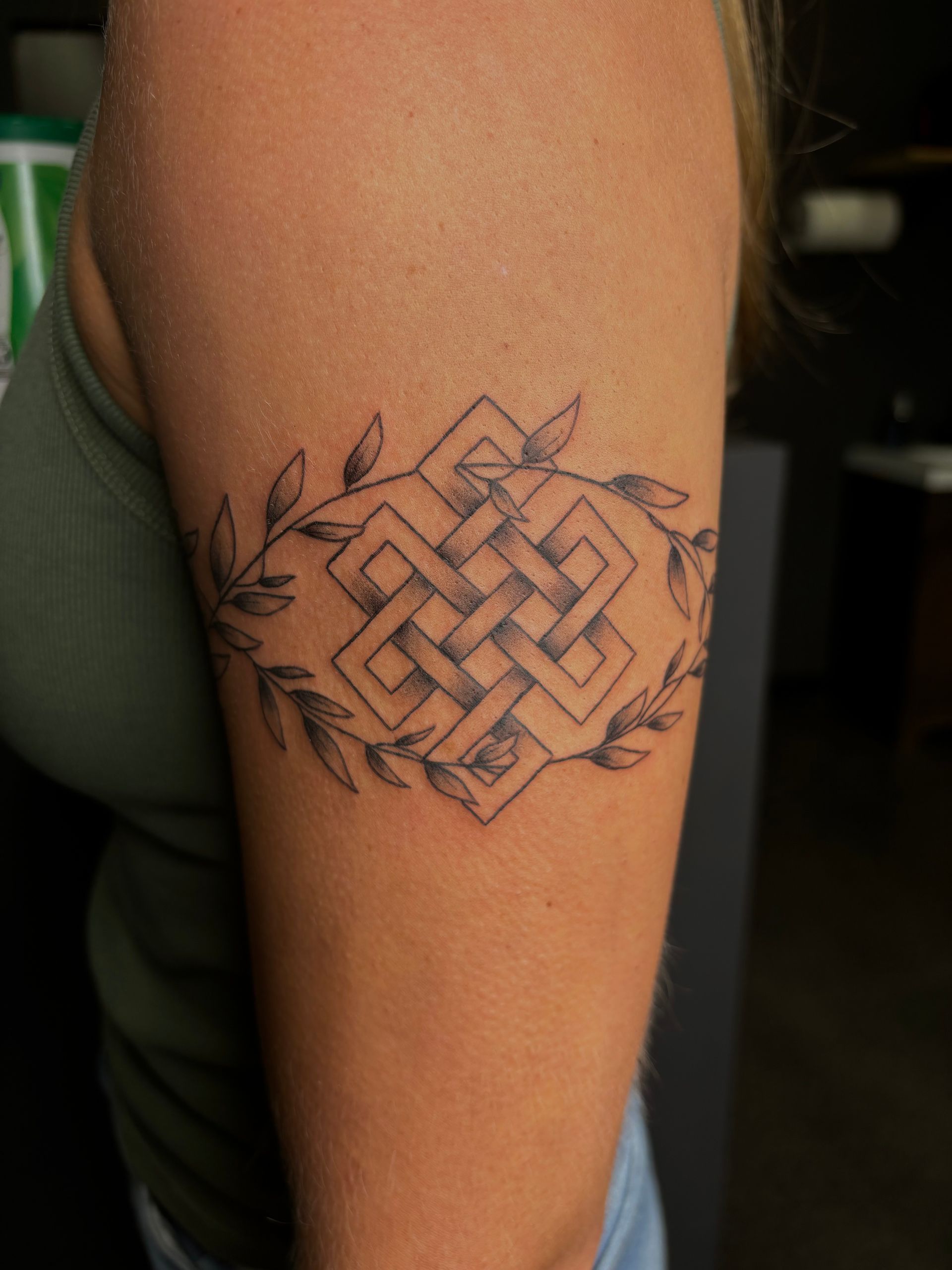 A woman has a celtic knot tattoo on her arm