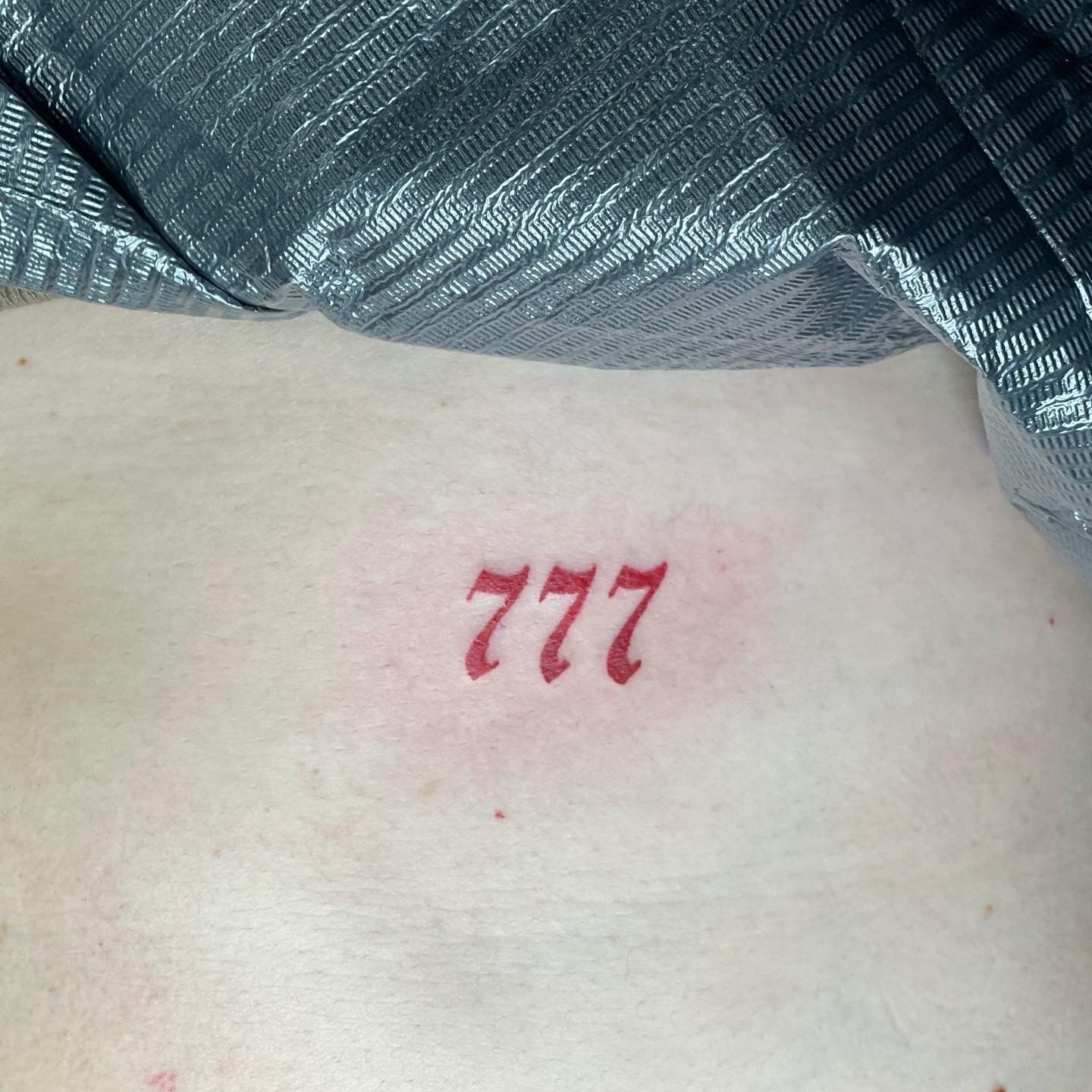 A person has a tattoo on their back that says 777