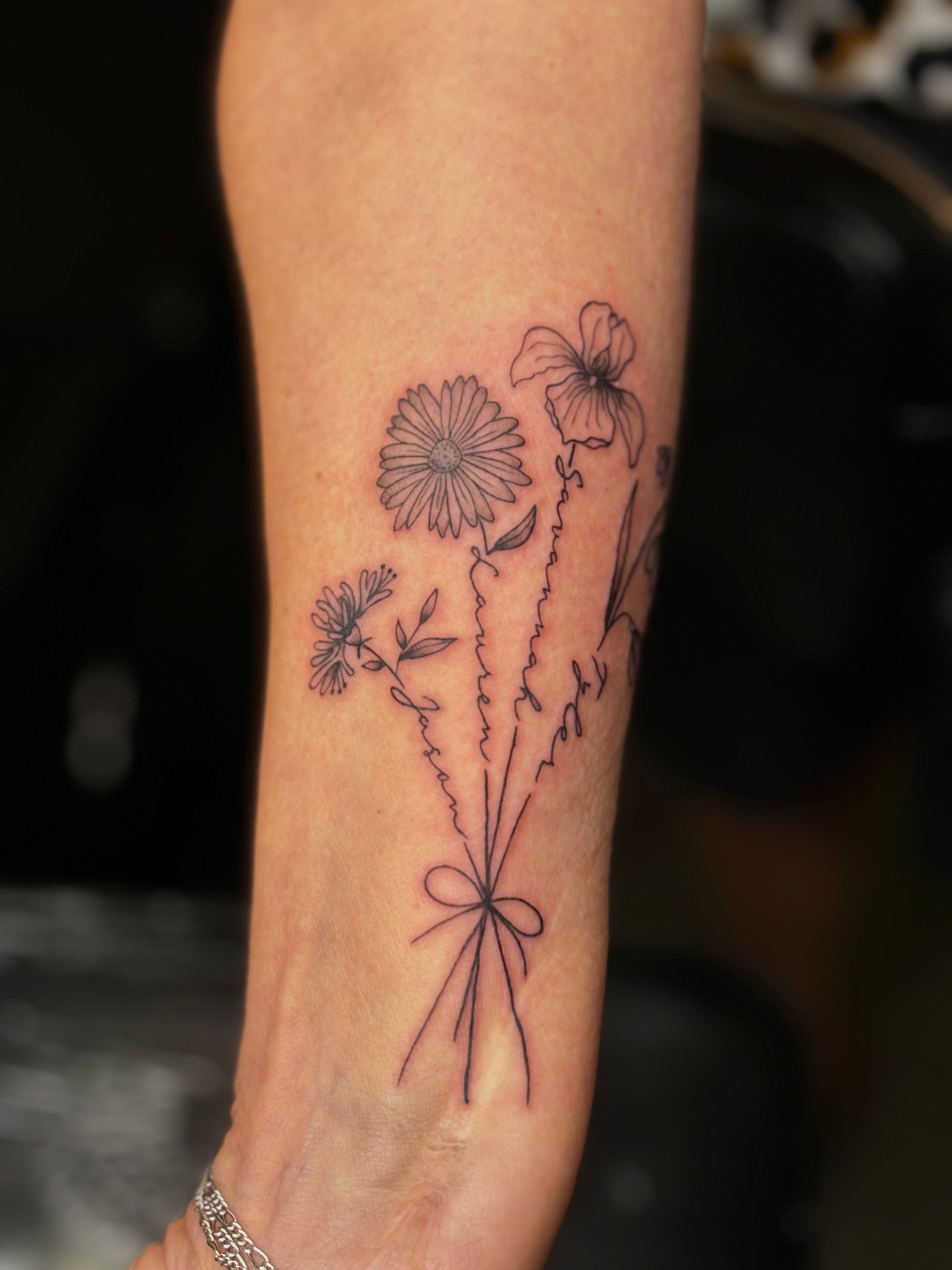 A woman has a tattoo of a bouquet of flowers on her arm