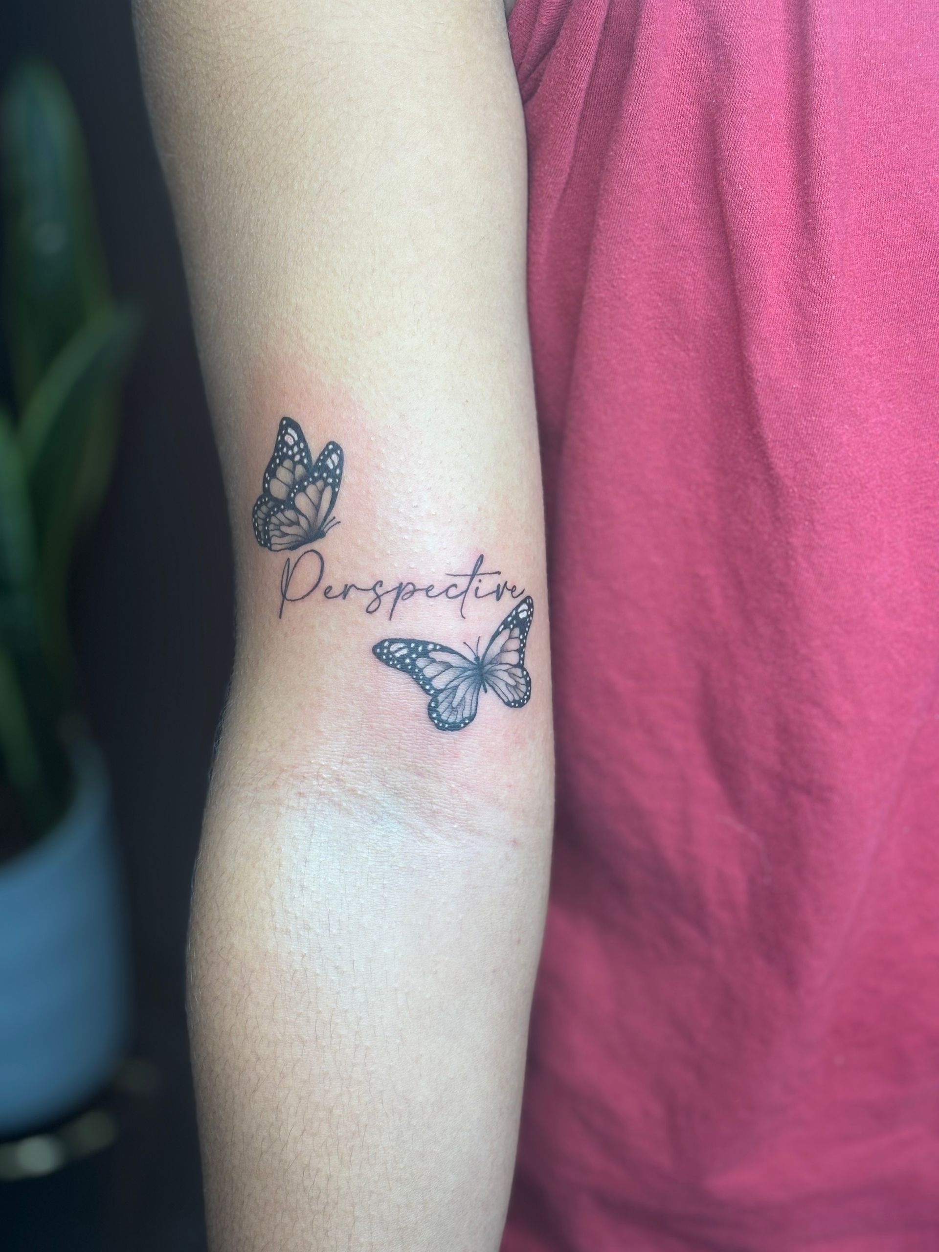 A woman has a tattoo of two butterflies on her elbow.