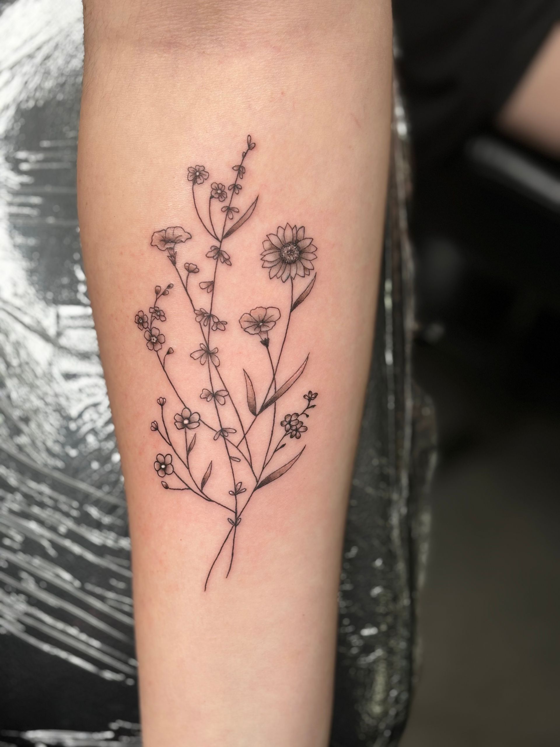 A woman has a tattoo of flowers on her forearm