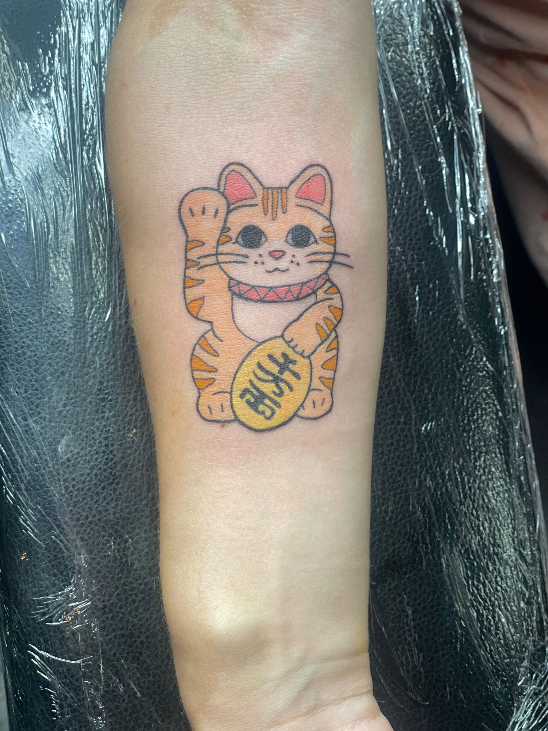 A person has a tattoo of a cat on their arm