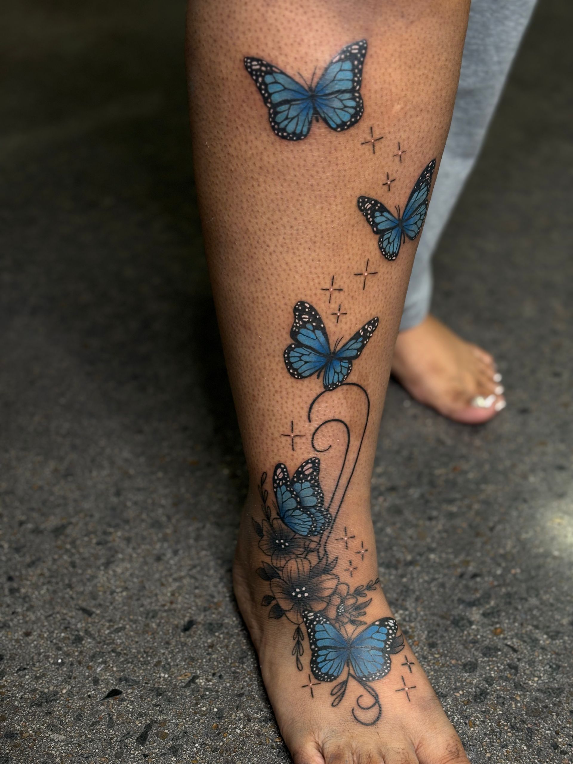 A woman has a tattoo of blue butterflies on her leg