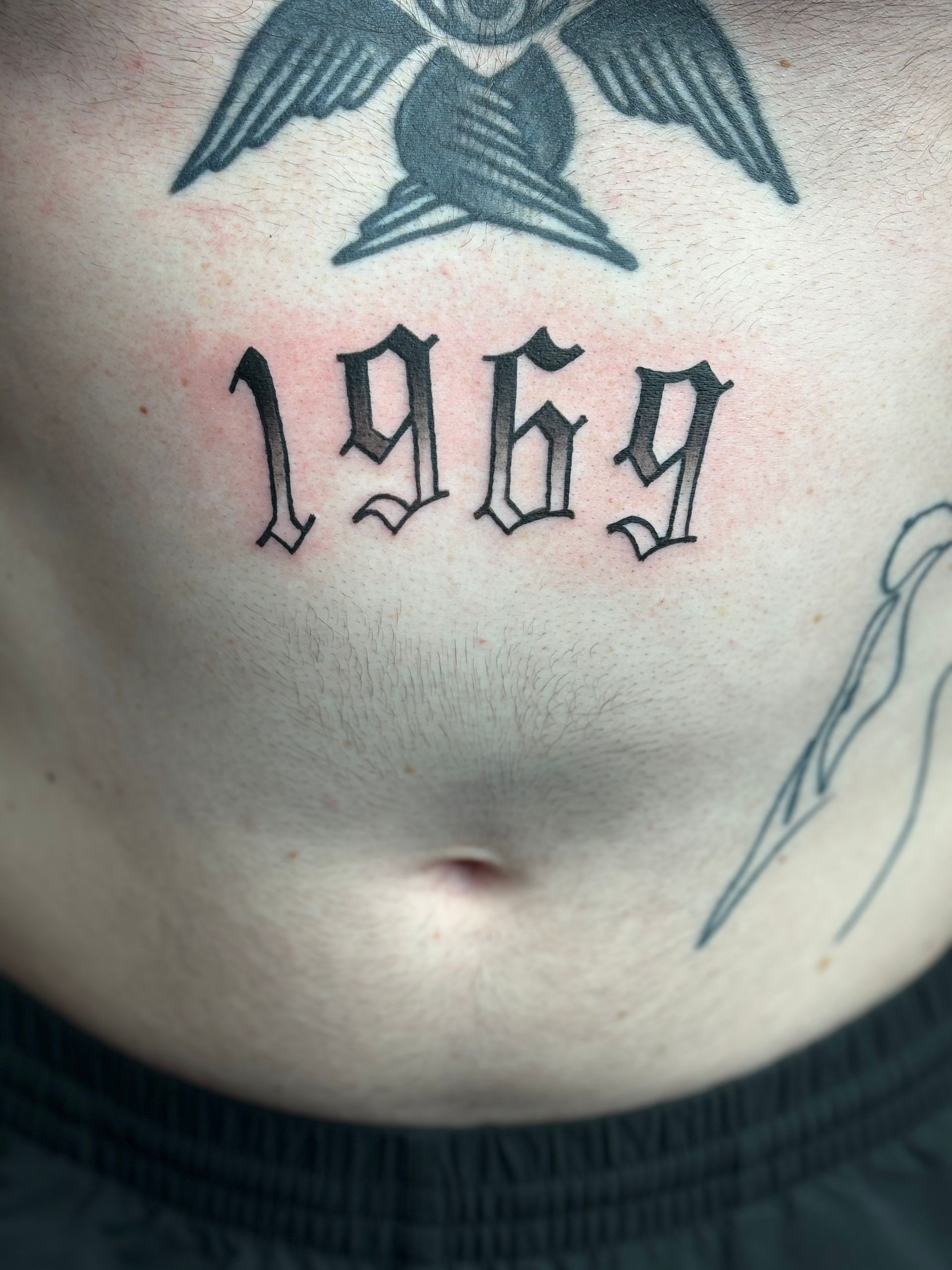 A person has a tattoo on their chest that says 1969