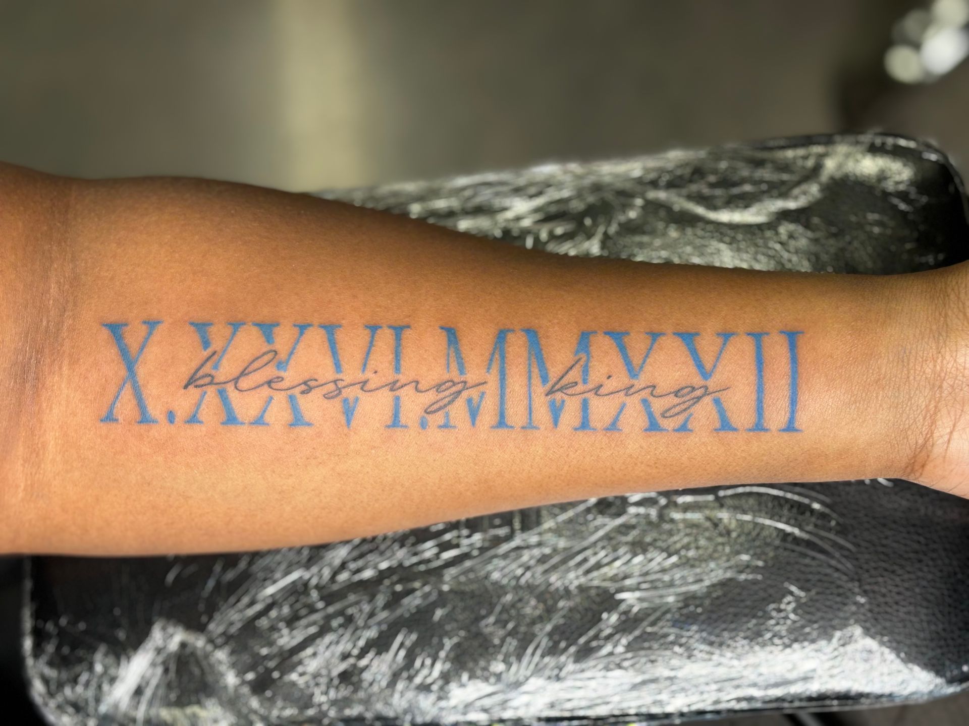 A person has a tattoo on their arm with roman numerals.