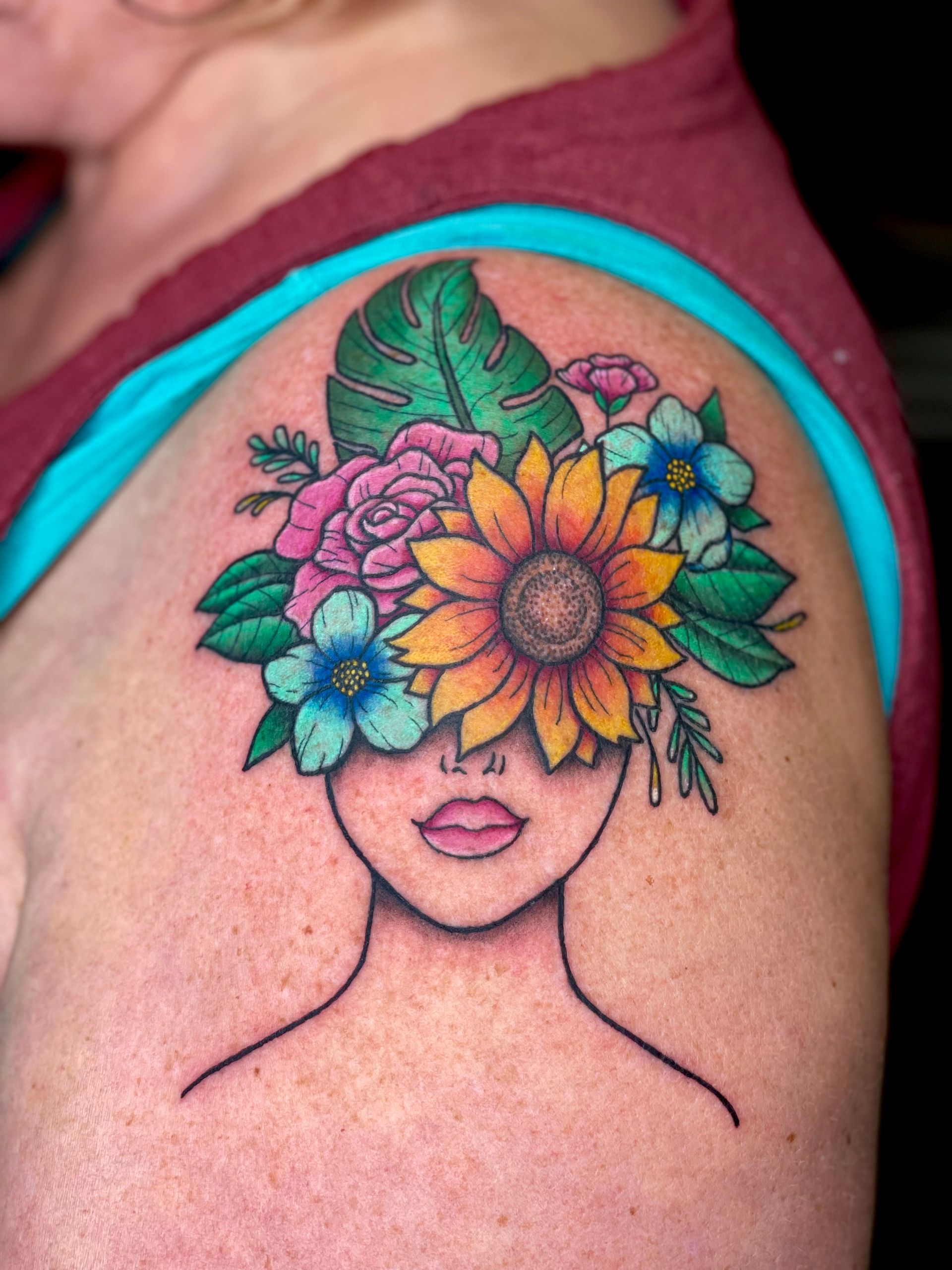 A woman has a tattoo of a woman with flowers in her hair
