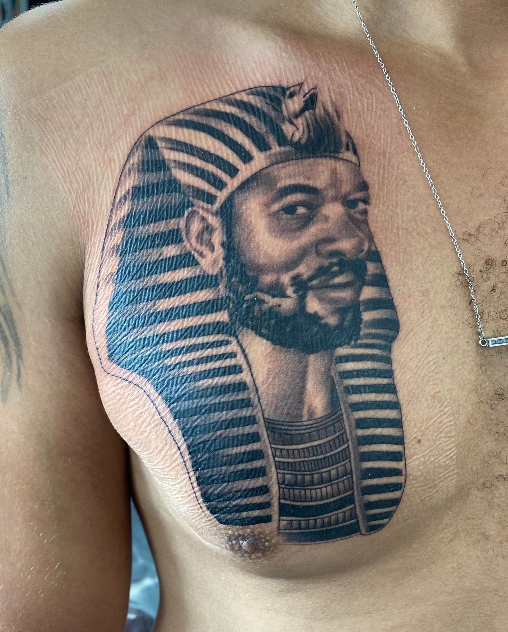 A man has a tattoo of a pharaoh on his chest.
