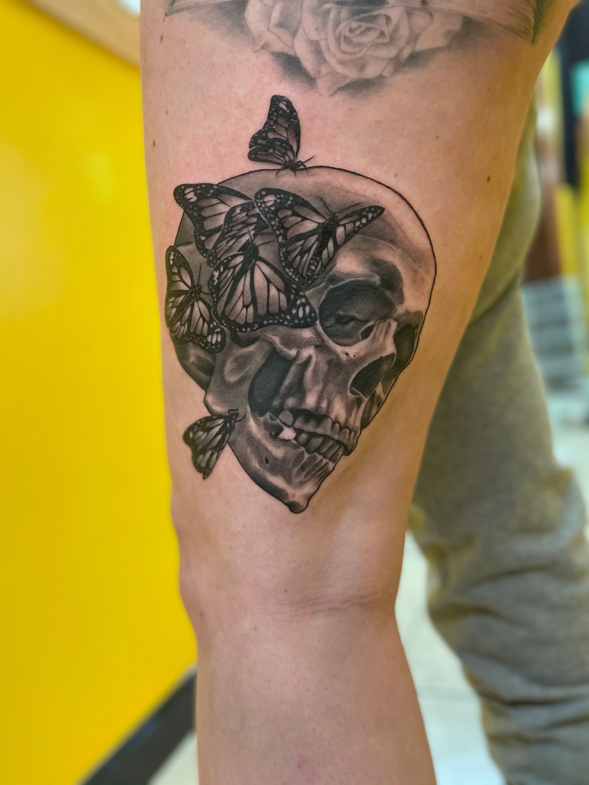 A tattoo of a skull with butterflies on it