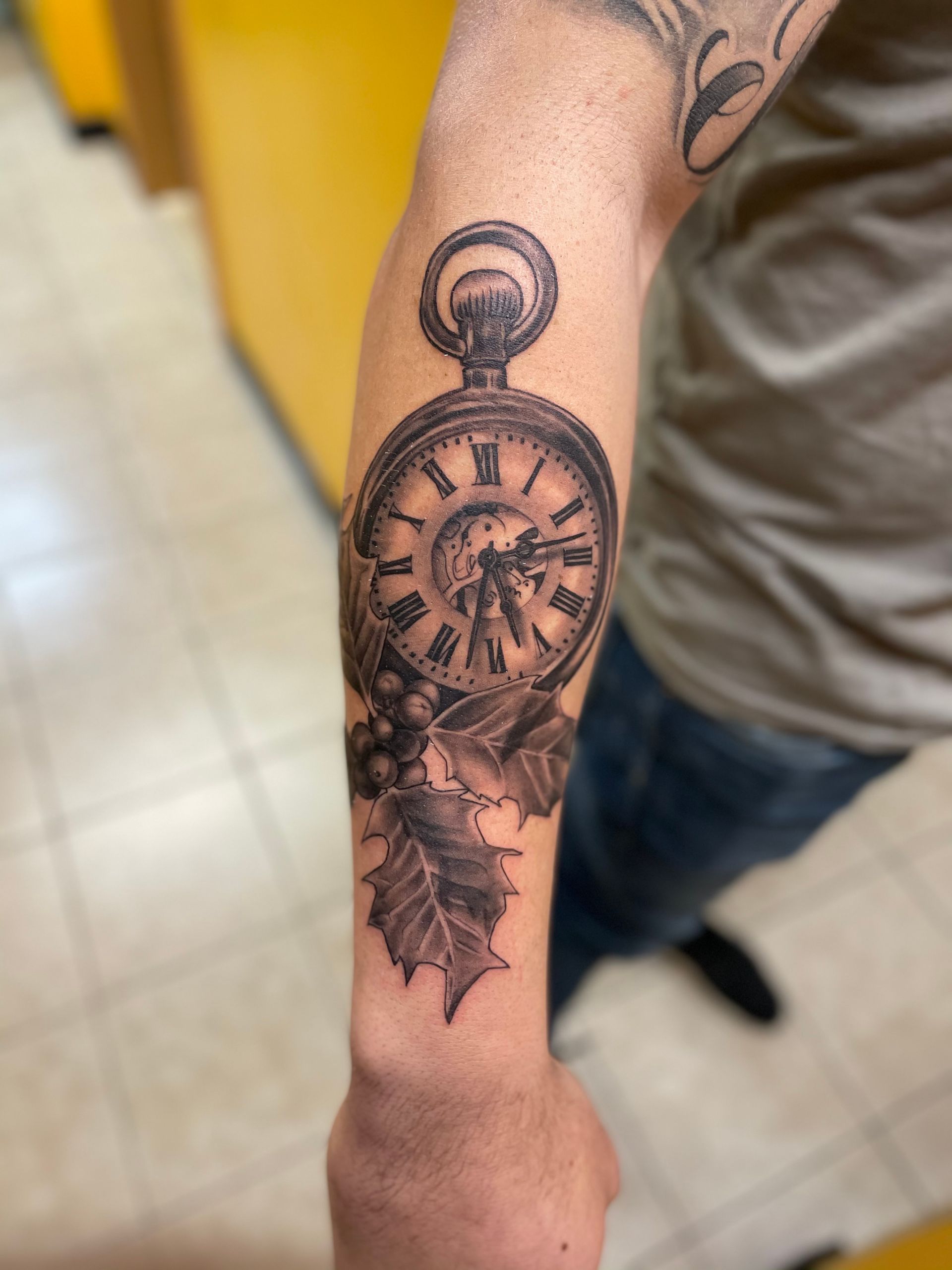 A man has a tattoo of a pocket watch on his arm
