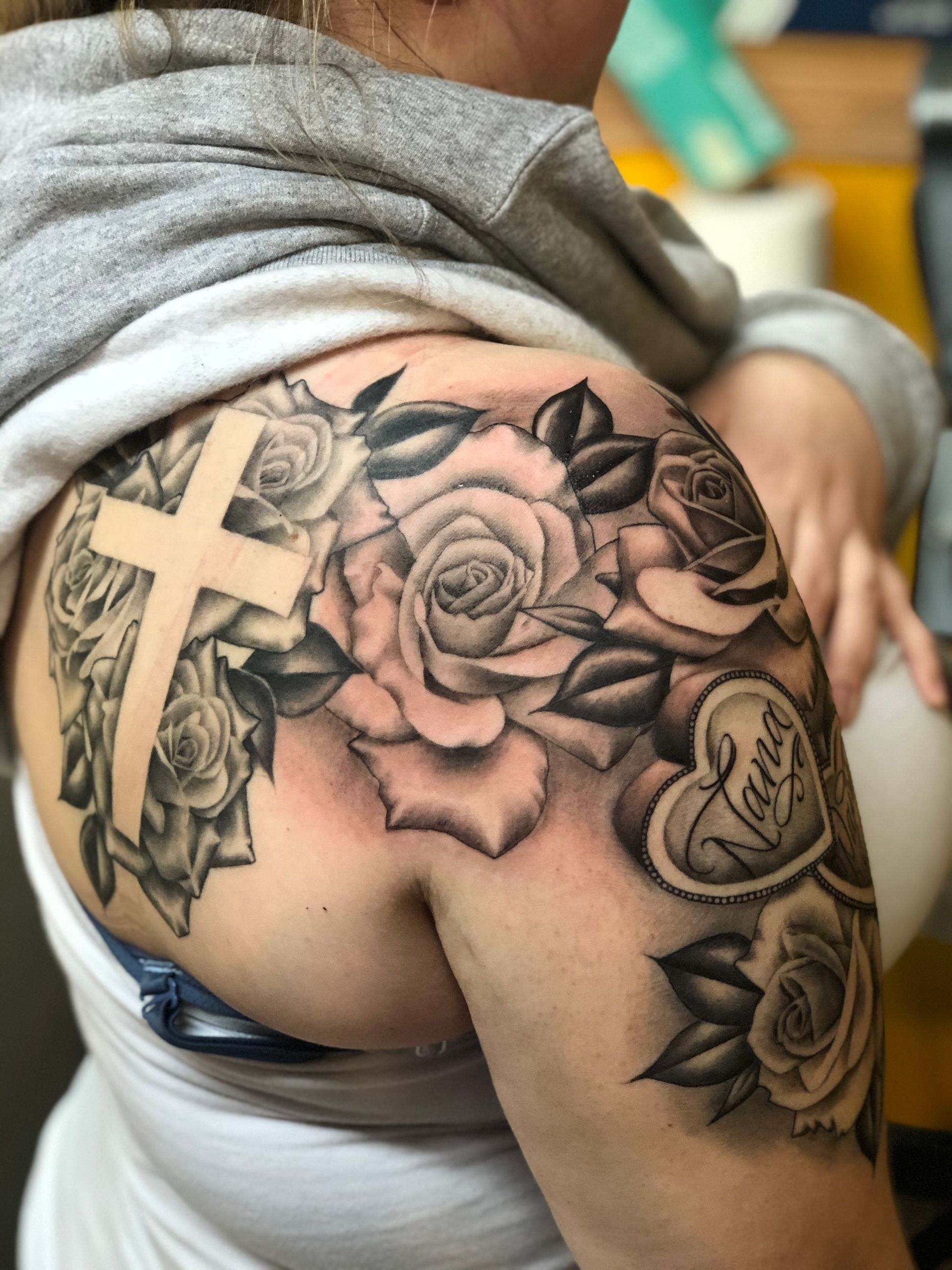 A woman has a tattoo of roses and a cross on her shoulder