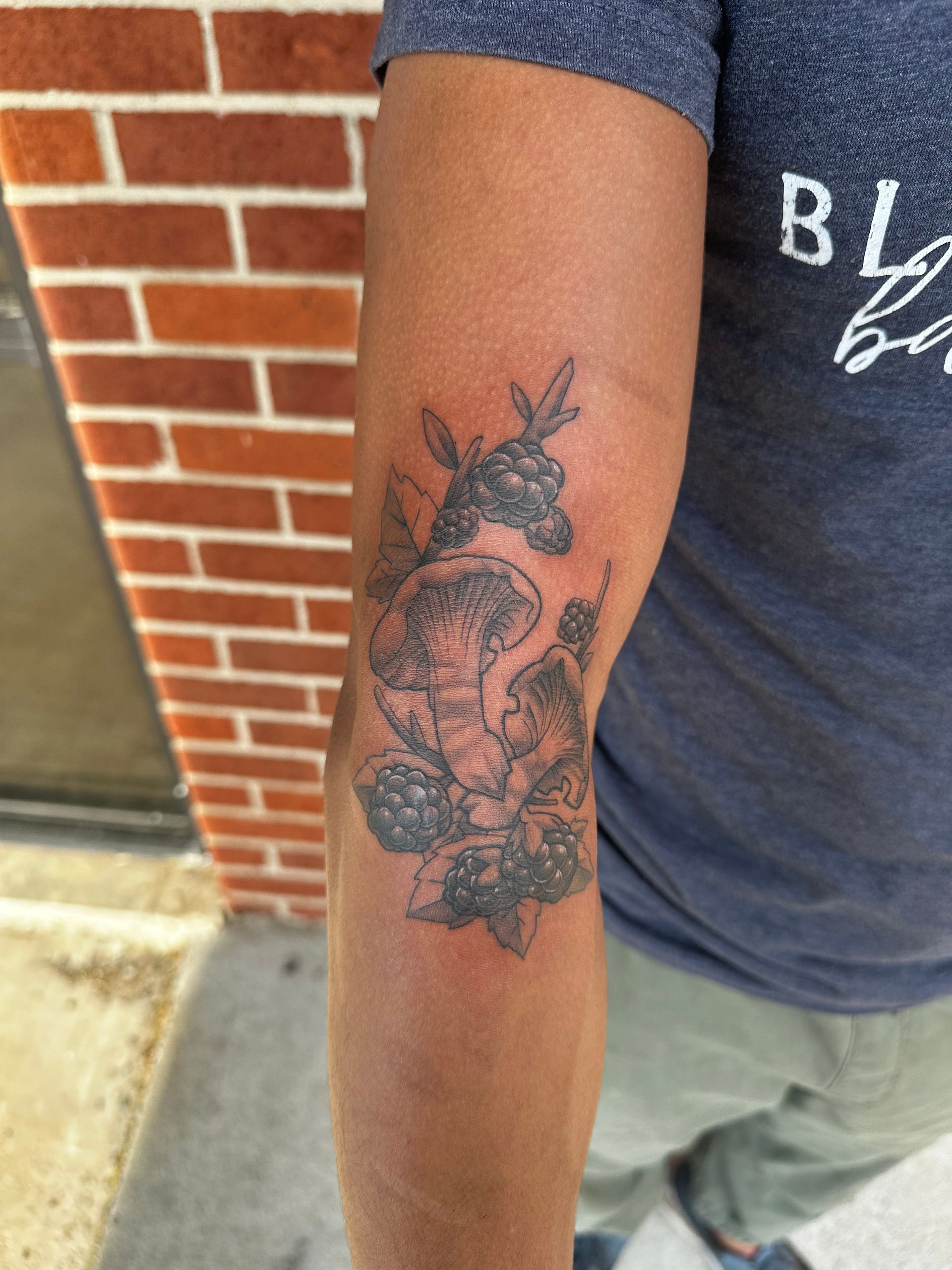 A person with a tattoo on their arm with a brick wall in the background