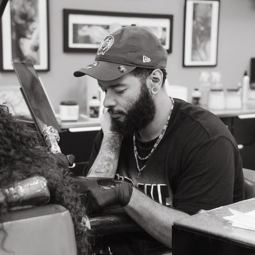 A man with a beard is sitting at a desk in front of a laptop computer.