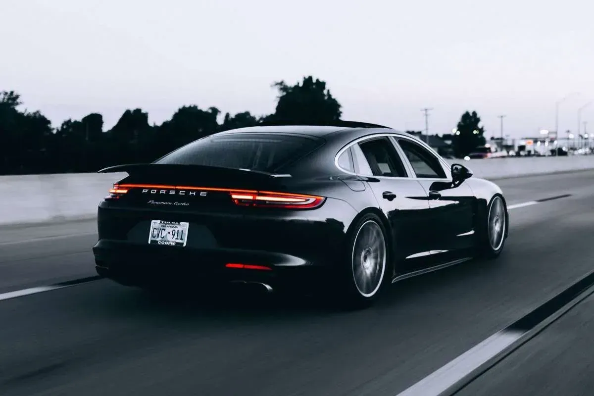 Black Porsche Panamera driving on highway, rear view.