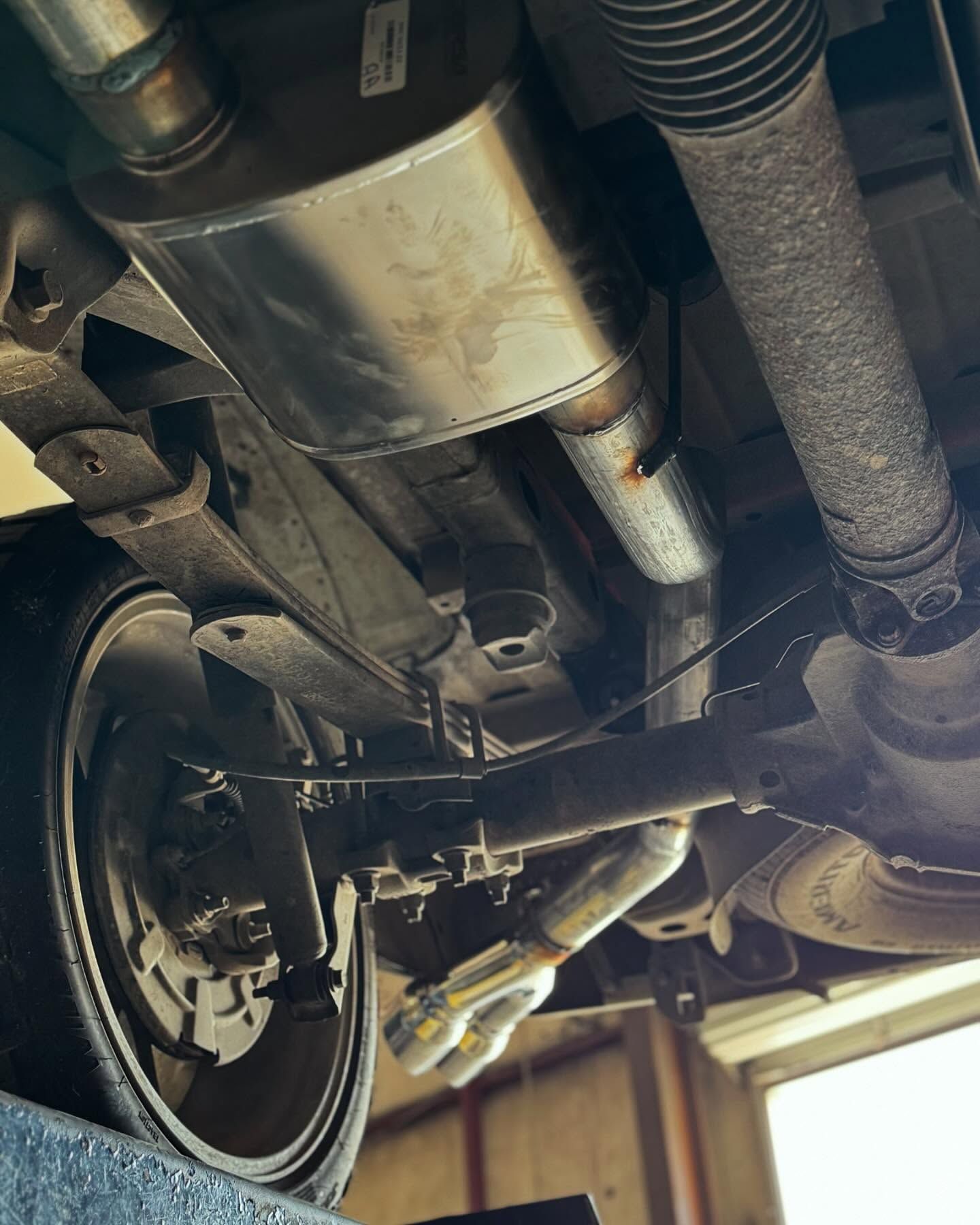 Underneath view of a car, showing exhaust system components, muffler, and rear axle.