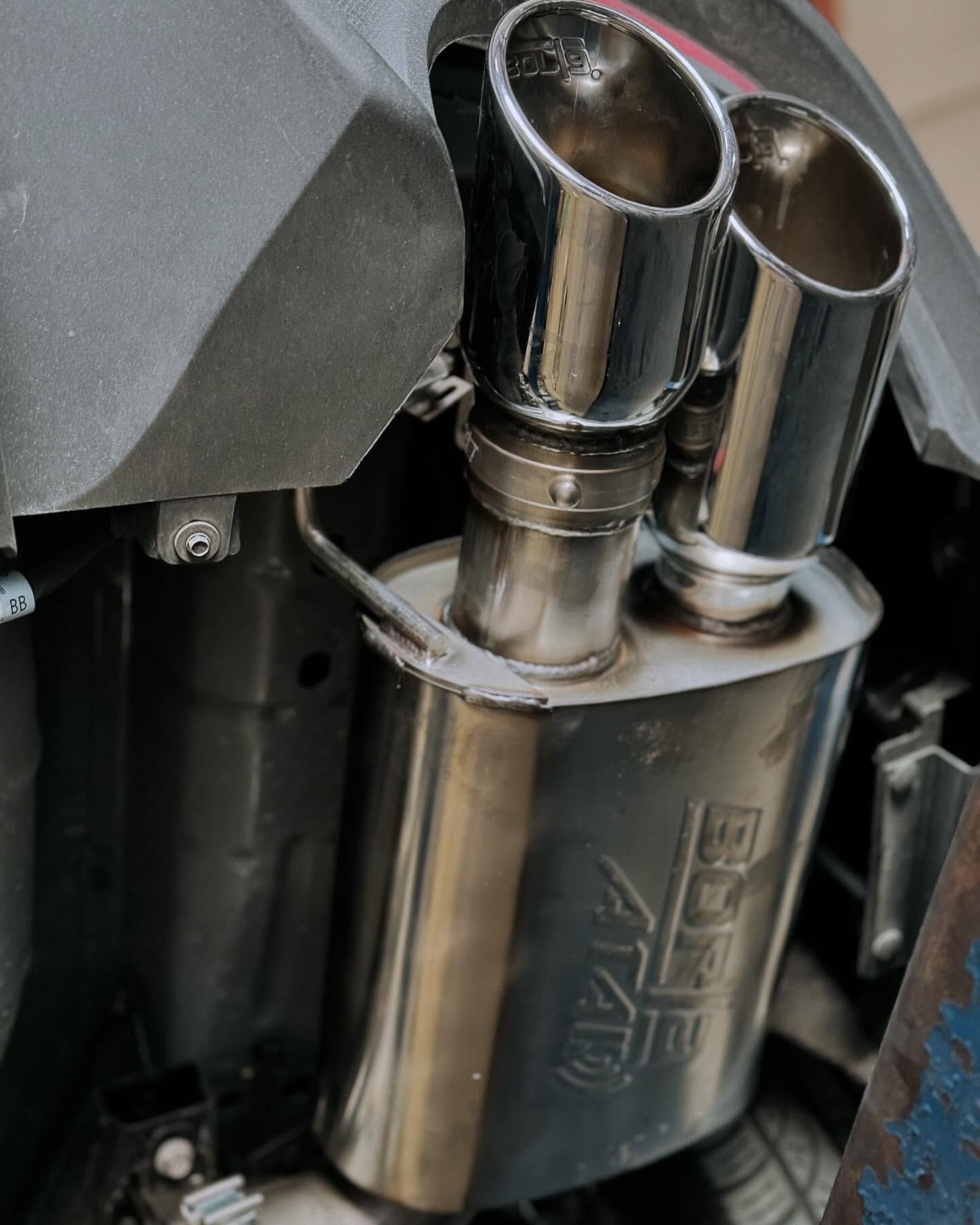 Shiny chrome dual exhaust pipes on a silver muffler with 