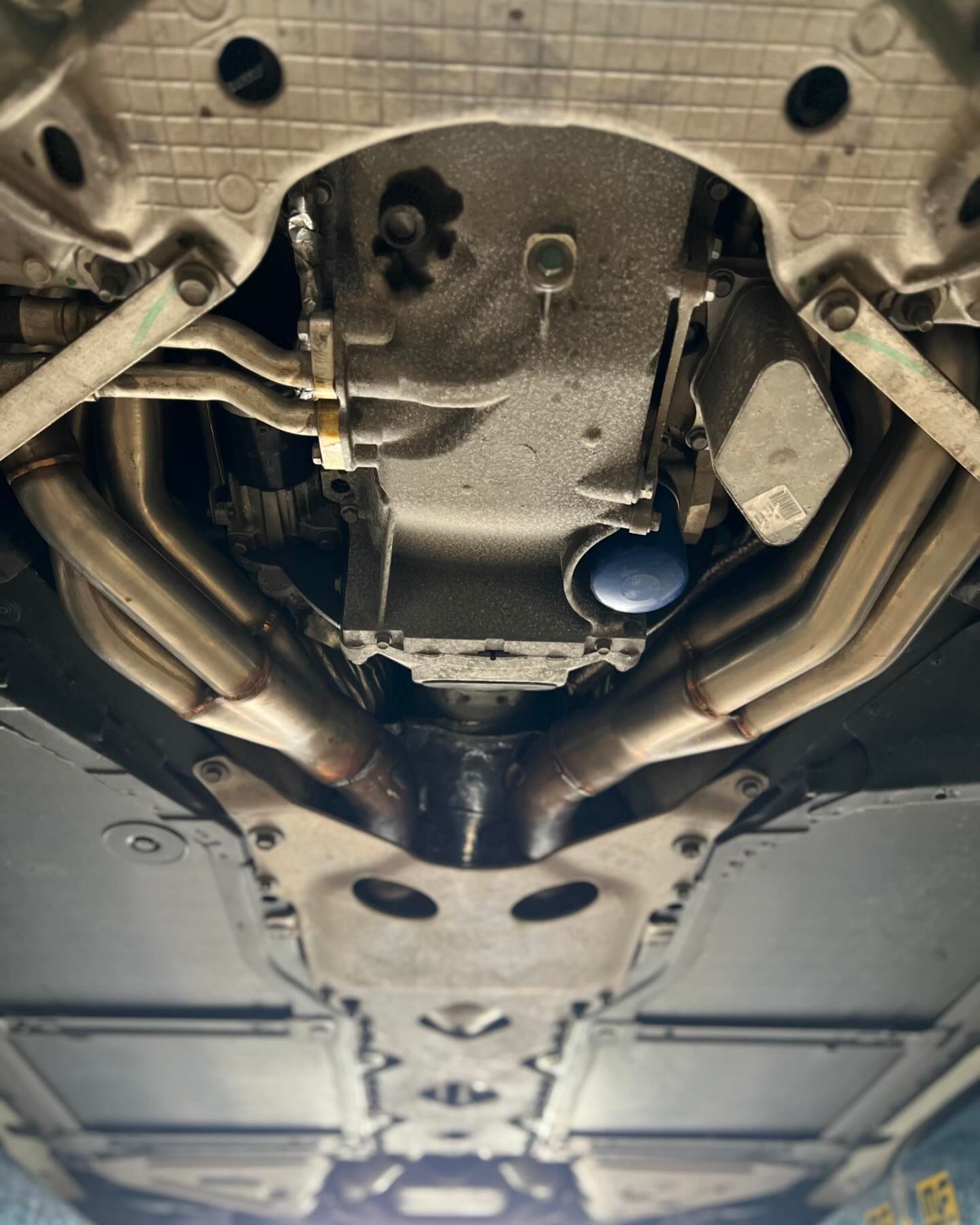 Underside of a car, showing exhaust pipes, oil pan, and other mechanical components.