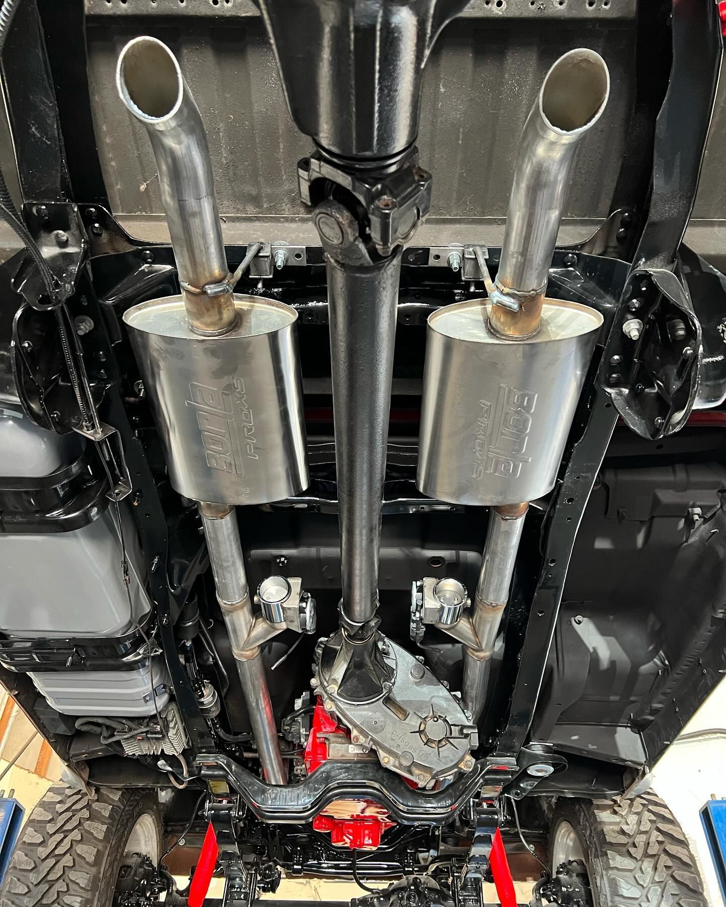 Underside view of a vehicle chassis, showing exhaust system, drive shaft, and differential.