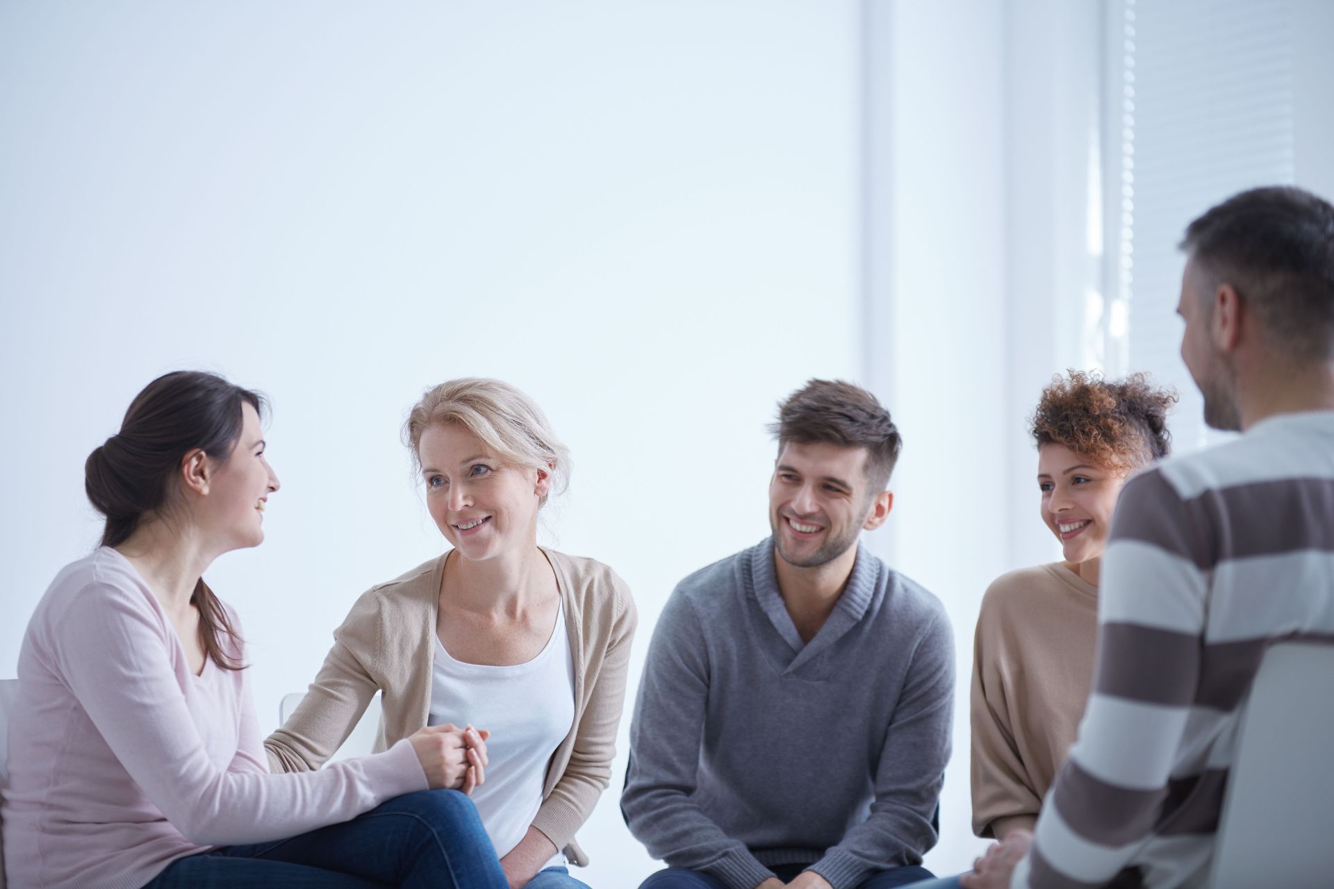 A group of people are sitting in a circle talking to each other.
