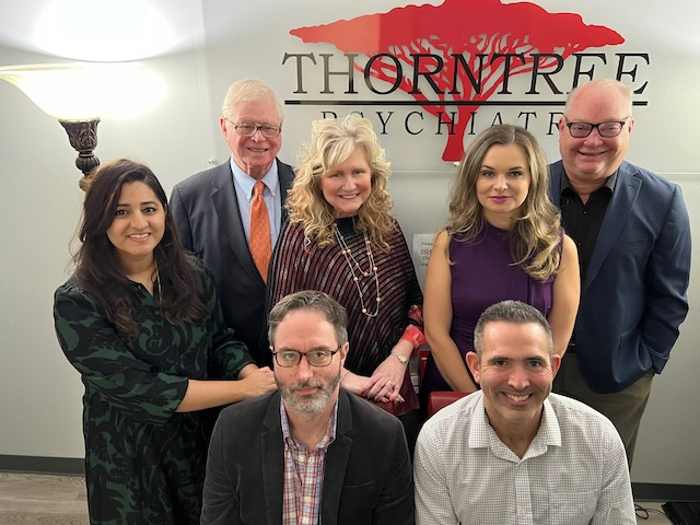 A group of people standing in front of a sign that says thorntree