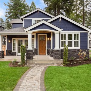 Blue house with stone accents, white trim, and a brick pathway leading to the front door.
