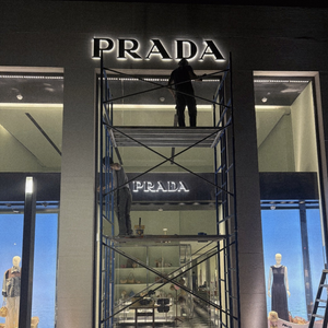 Workers on scaffolding are painting a commercial building.