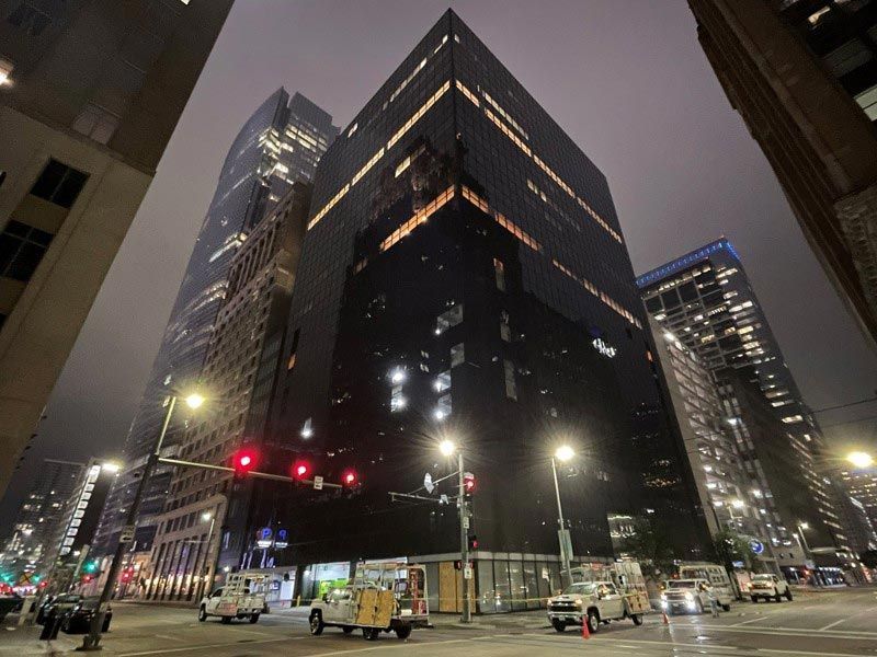 A city street at night with a large building in the background