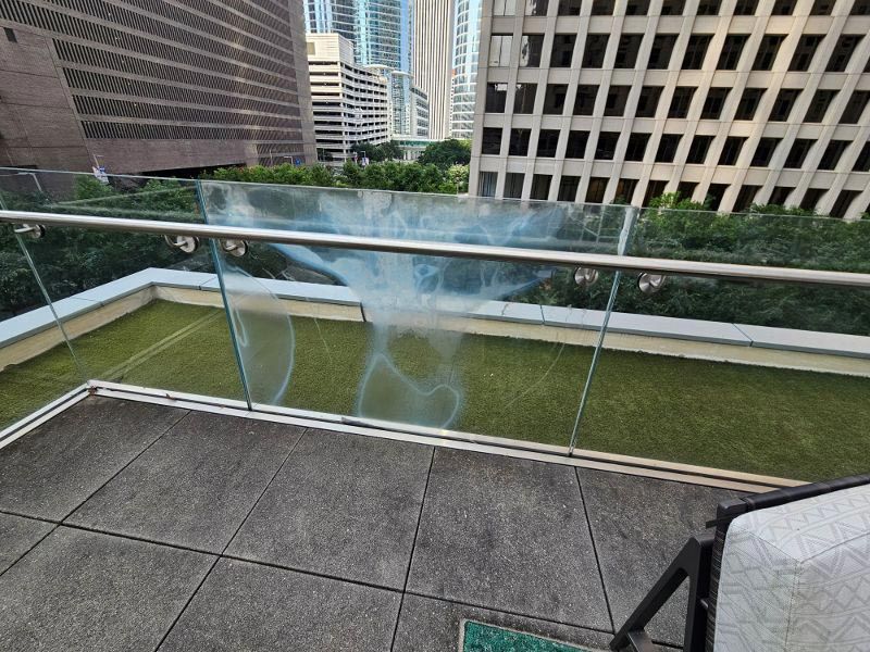 A balcony with a glass railing and a view of a city.