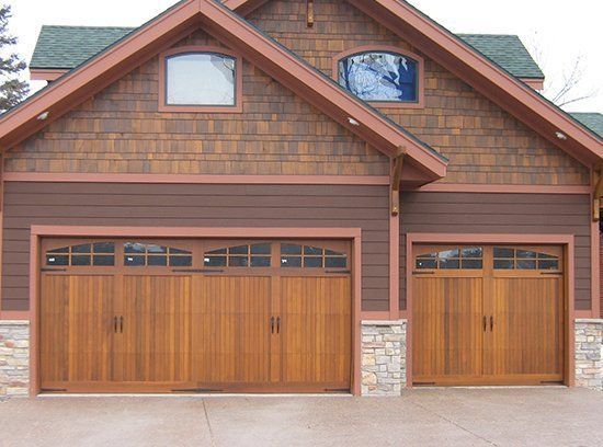 Two-car wooden garage with brown siding and stone accents on a suburban home