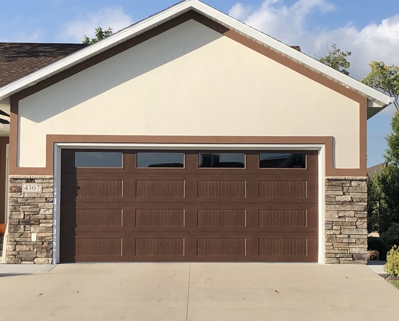 Suburban house exterior with a brown double garage door and stone trim