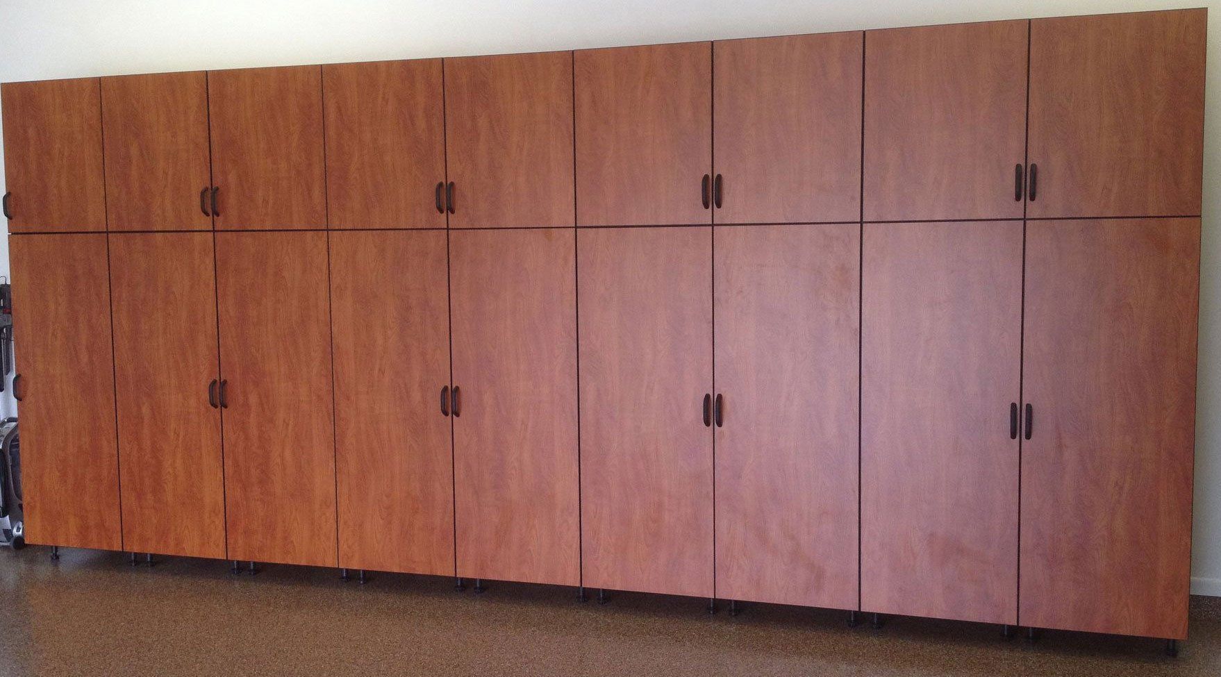 Row of light brown wooden storage cabinets with dark handles against a wall