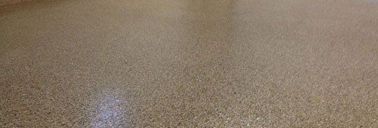 Close-up of a tan speckled carpet with a small bright white reflection near the center left.