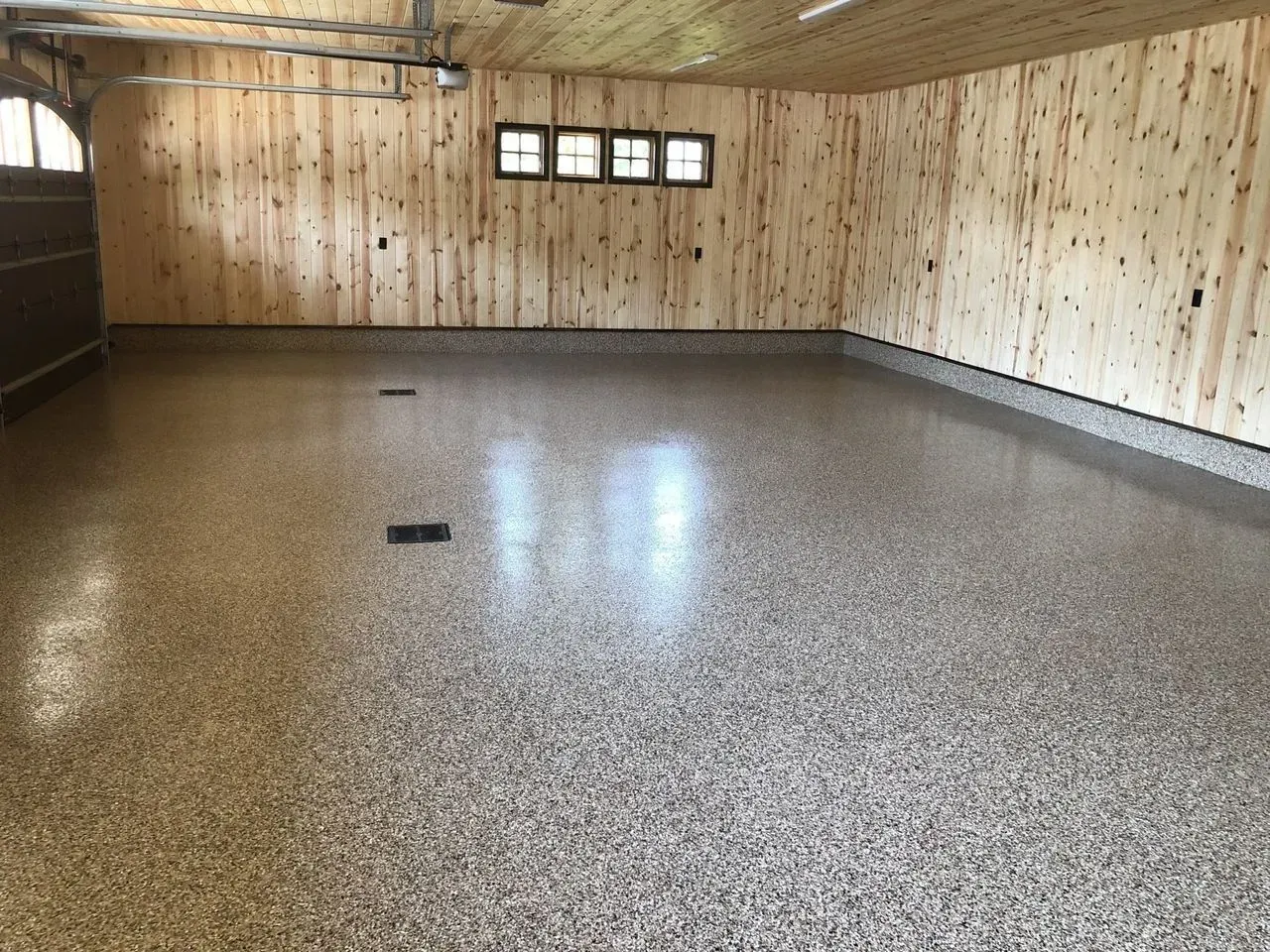 Empty basement with unfinished wood walls, exposed beams, and a polished concrete floor.