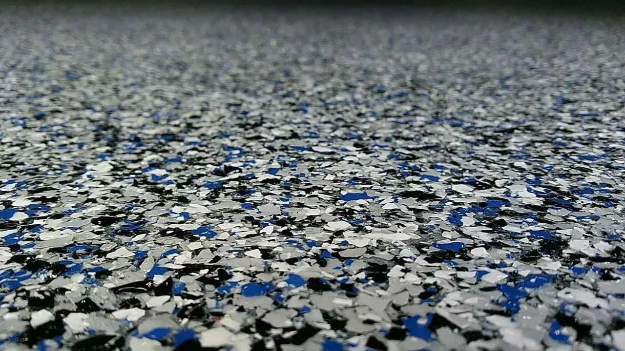 Ground-level view of a rough, gray surface scattered with small blue and white fragments