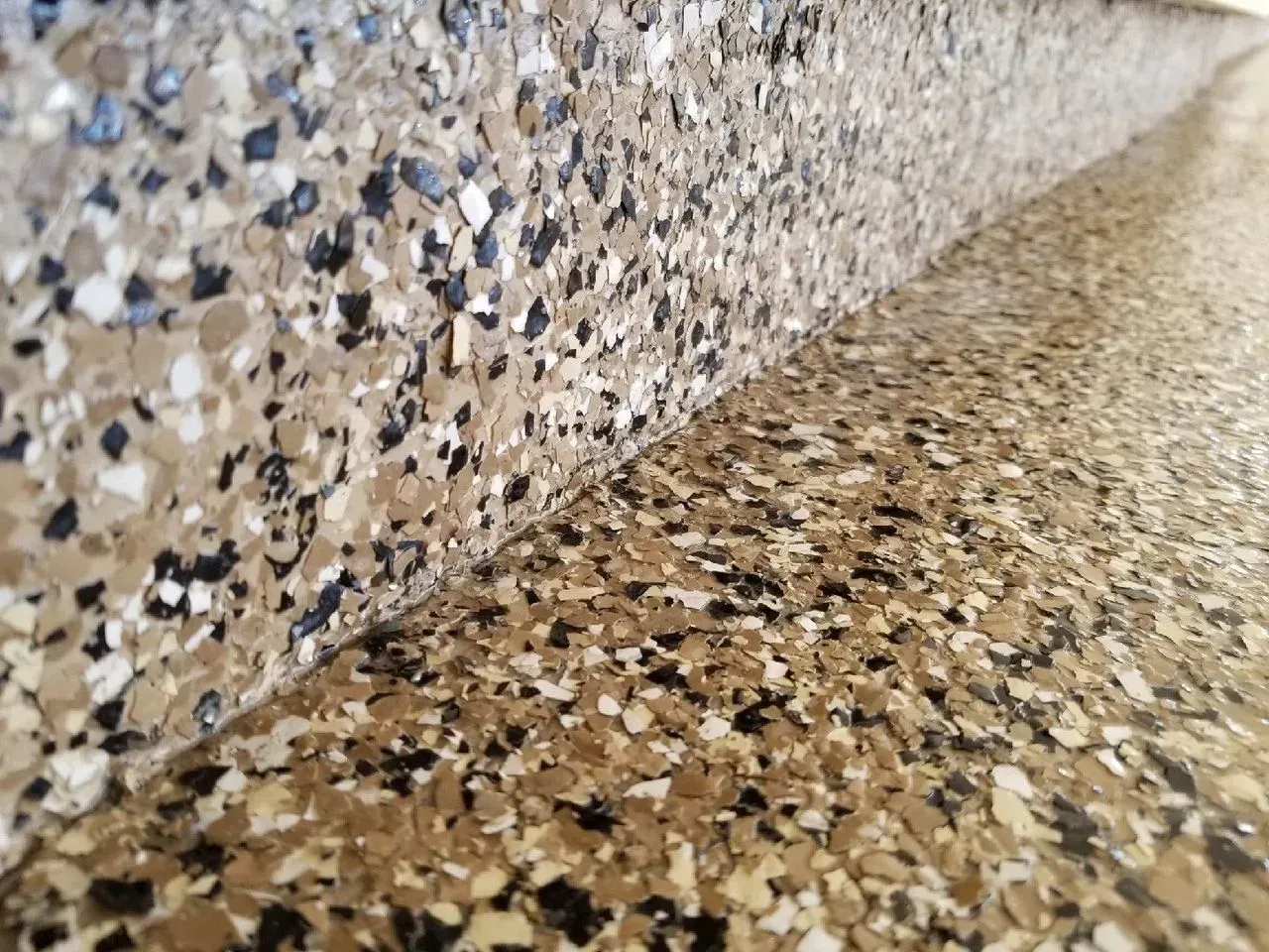 Close-up of a speckled terrazzo surface with a curved wall and floor corner
