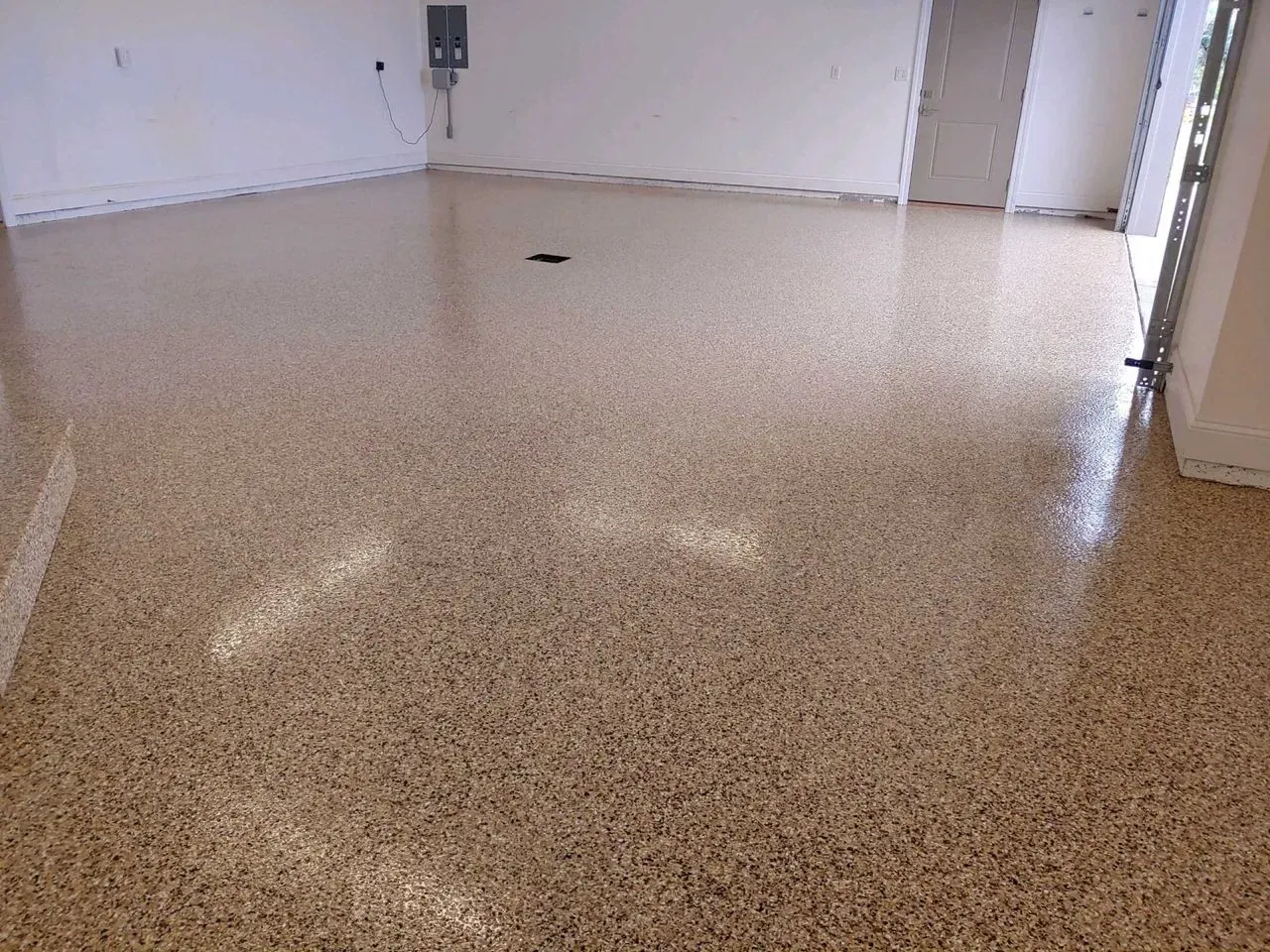 Empty garage with speckled epoxy floor and white walls