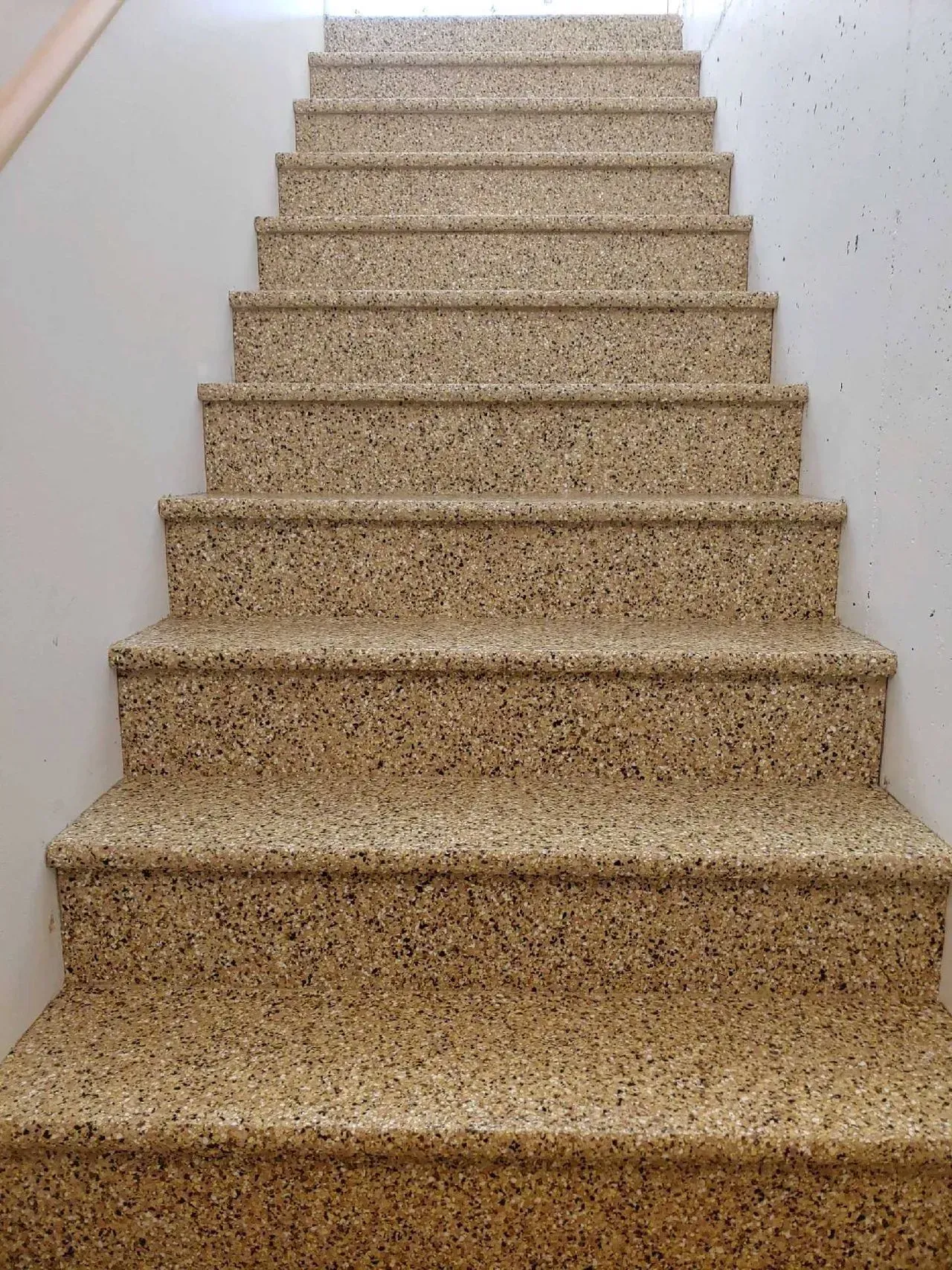 Carpeted indoor staircase with white walls, viewed from the bottom up