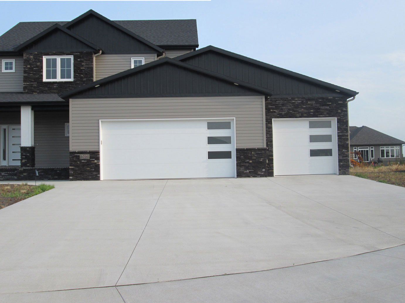 Modern house with a large sloped driveway and two white garage doors