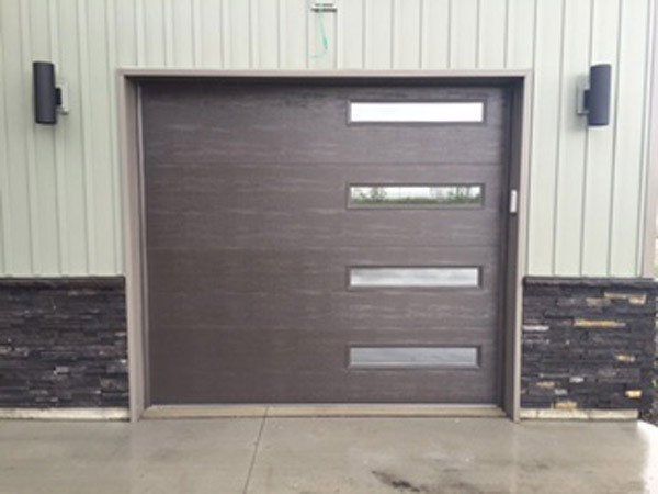 Closed brown garage-style door with small horizontal windows in a metal-sided building.