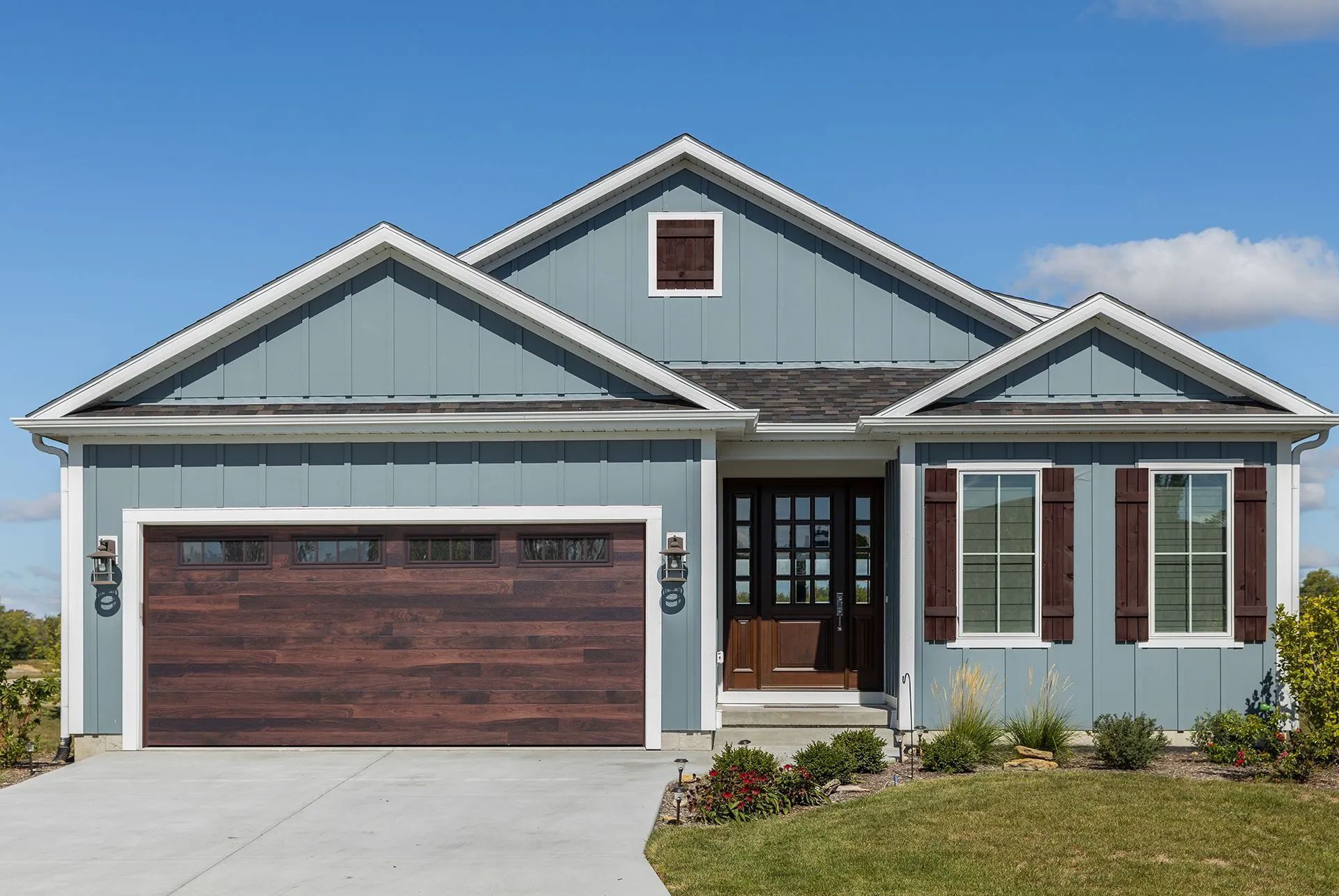 Blue-gray suburban house with a brown garage door and white trim, viewed from the front.