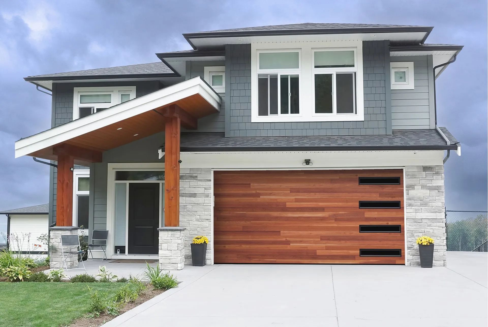 Modern two-story house with gray siding, wood garage door, and white trim