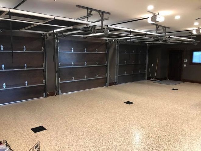 Partially finished garage with open overhead door, exposed brick wall, and construction materials inside.