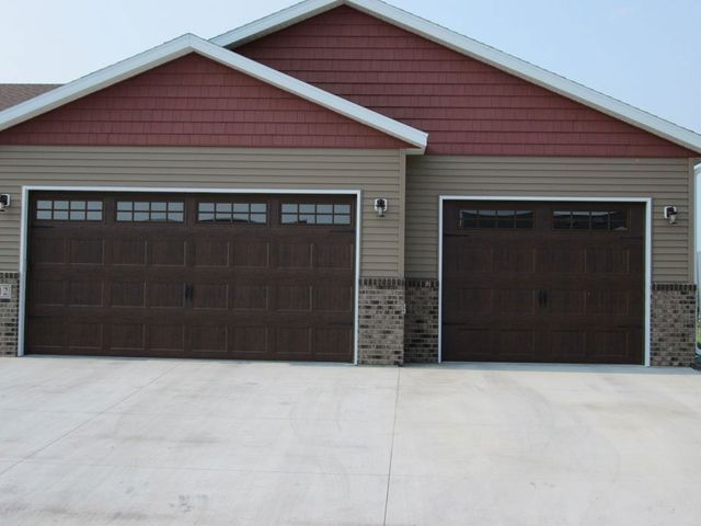 Two-car garage with brown doors and a red gable roof on a beige house facade