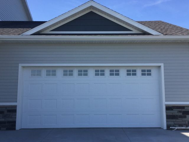 White double garage door on a house exterior with gray siding and stone accents