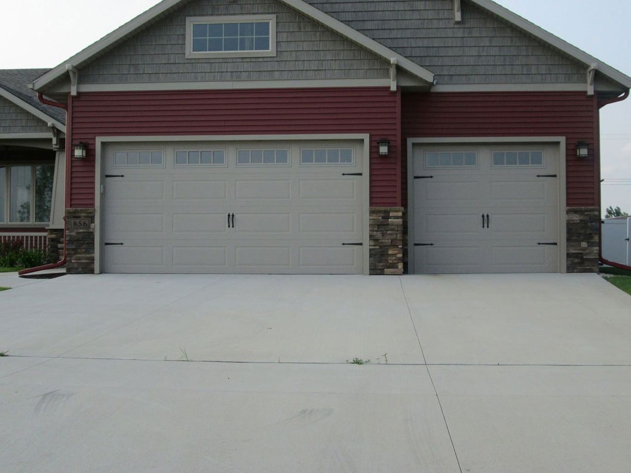 Suburban house with two gray garage doors and a wide concrete driveway